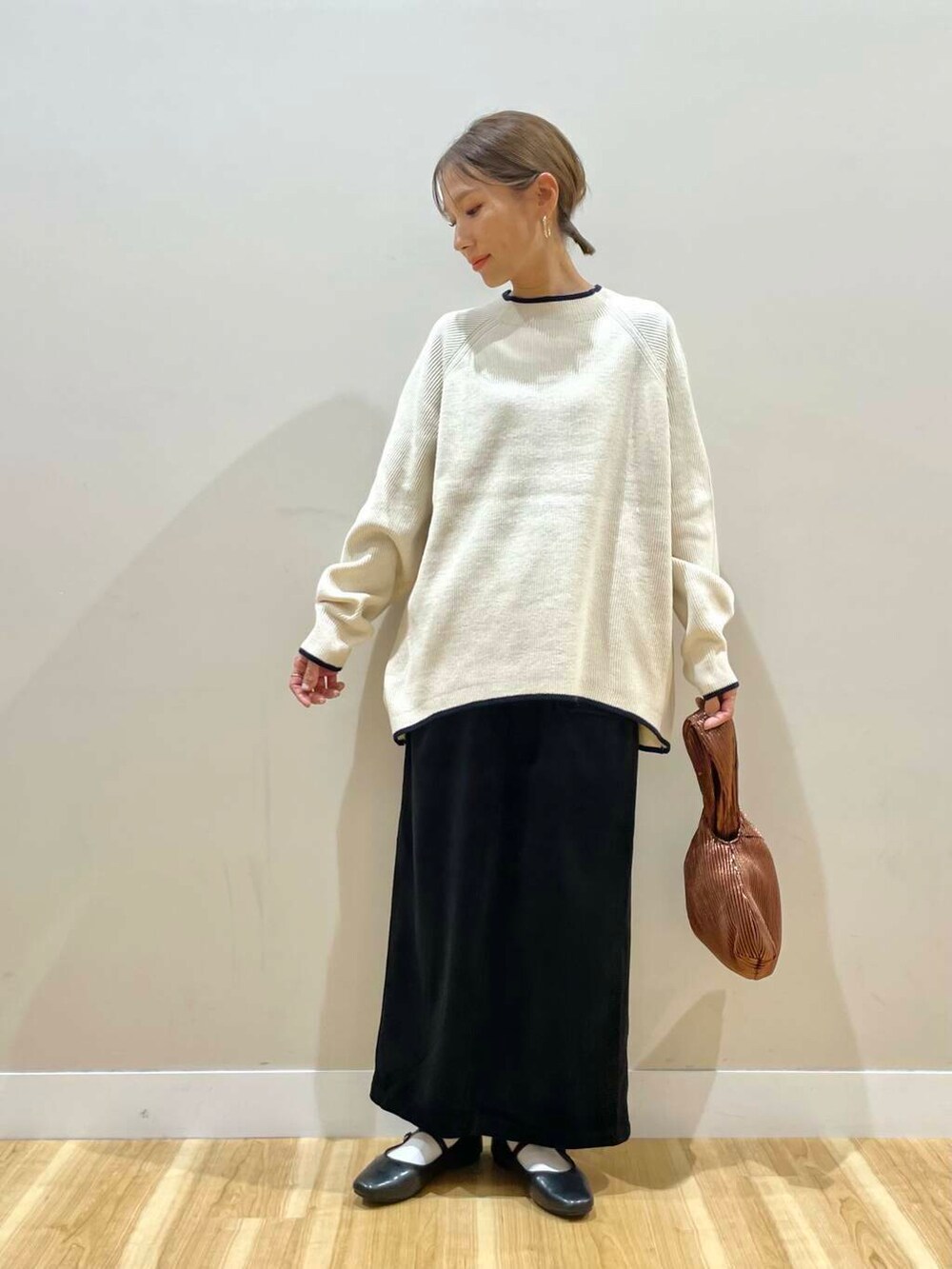 ブラック系のパンプス、ブラウン系のハンドバッグ、ホワイト系のニット/セーターを着用したレディースの冬コーディネートの6枚目の写真