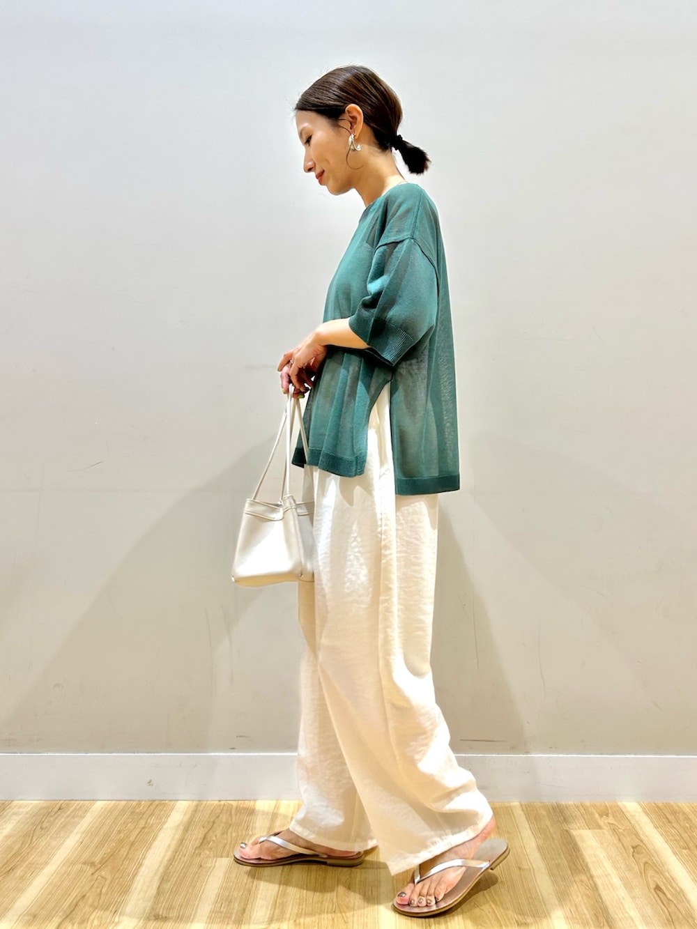 グリーン系のニット/セーター、ホワイト系のその他パンツを着用したレディースの夏コーディネートの3枚目の写真