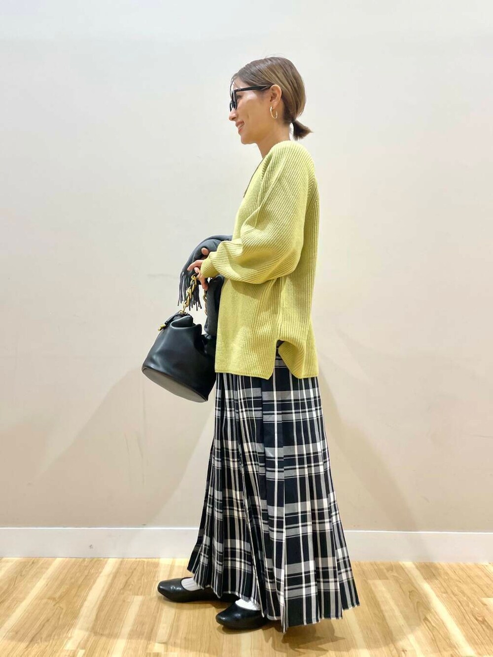 ブラック系のパンプス、ブラック系のショルダーバッグ、イエロー系のニット/セーターを着用したレディースの冬コーディネートの6枚目の写真