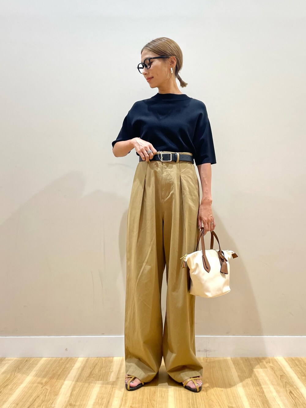 ブラック系のニット/セーター、イエロー系のチノパンツを着用したレディースの夏コーディネートの4枚目の写真