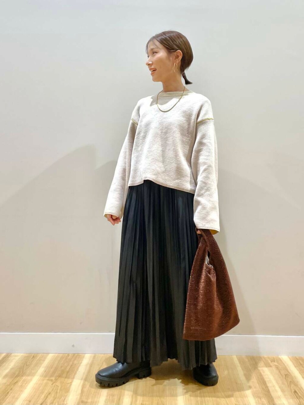 ブラック系のブーツ、ホワイト系のニット/セーター、ブラウン系のトートバッグを着用したレディースの冬コーディネートの9枚目の写真