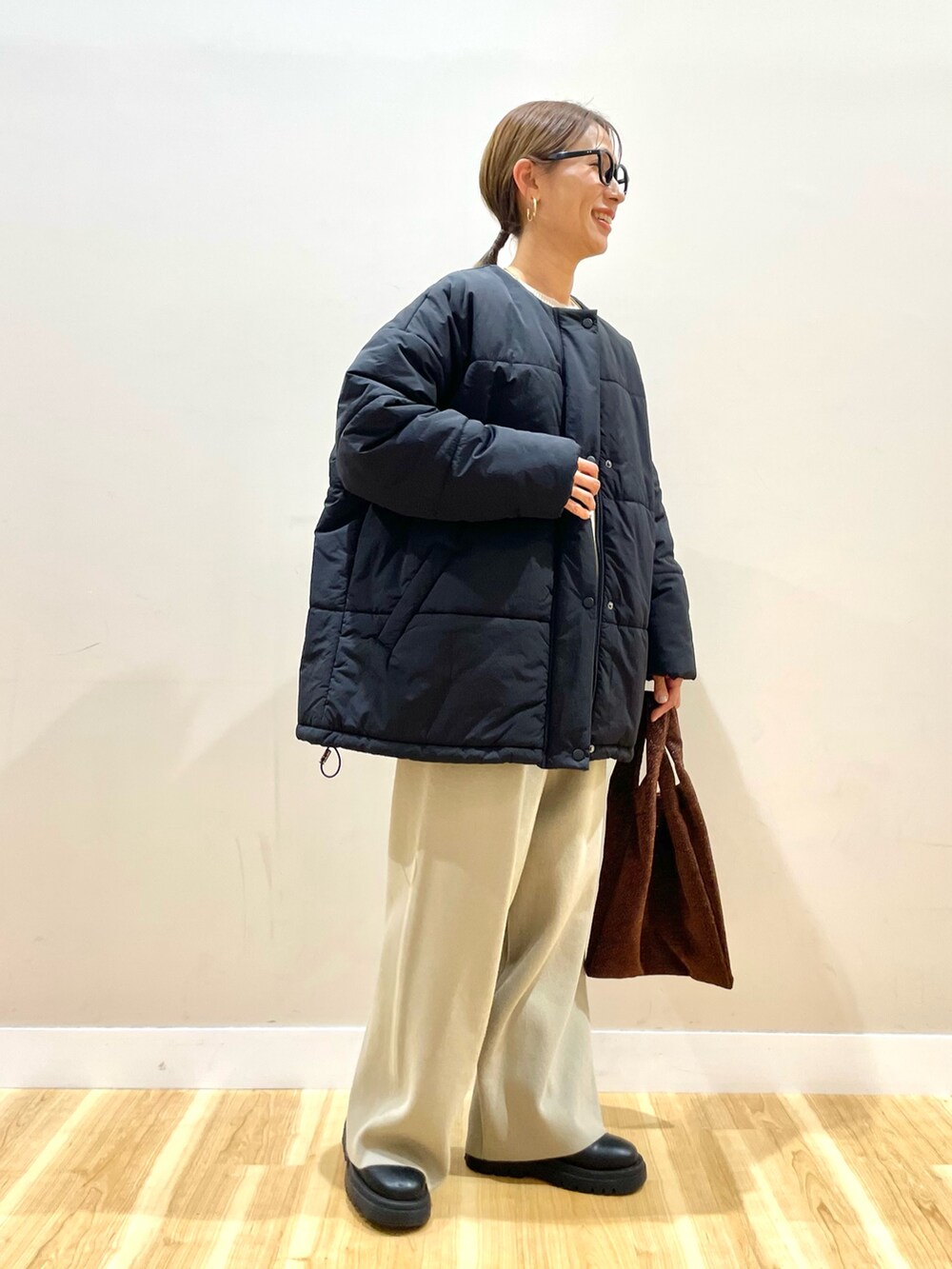 ブラック系のダウンジャケット/コート、ホワイト系のニット/セーター、ベージュ系のその他パンツを着用したレディースの冬コーディネートの2枚目の写真