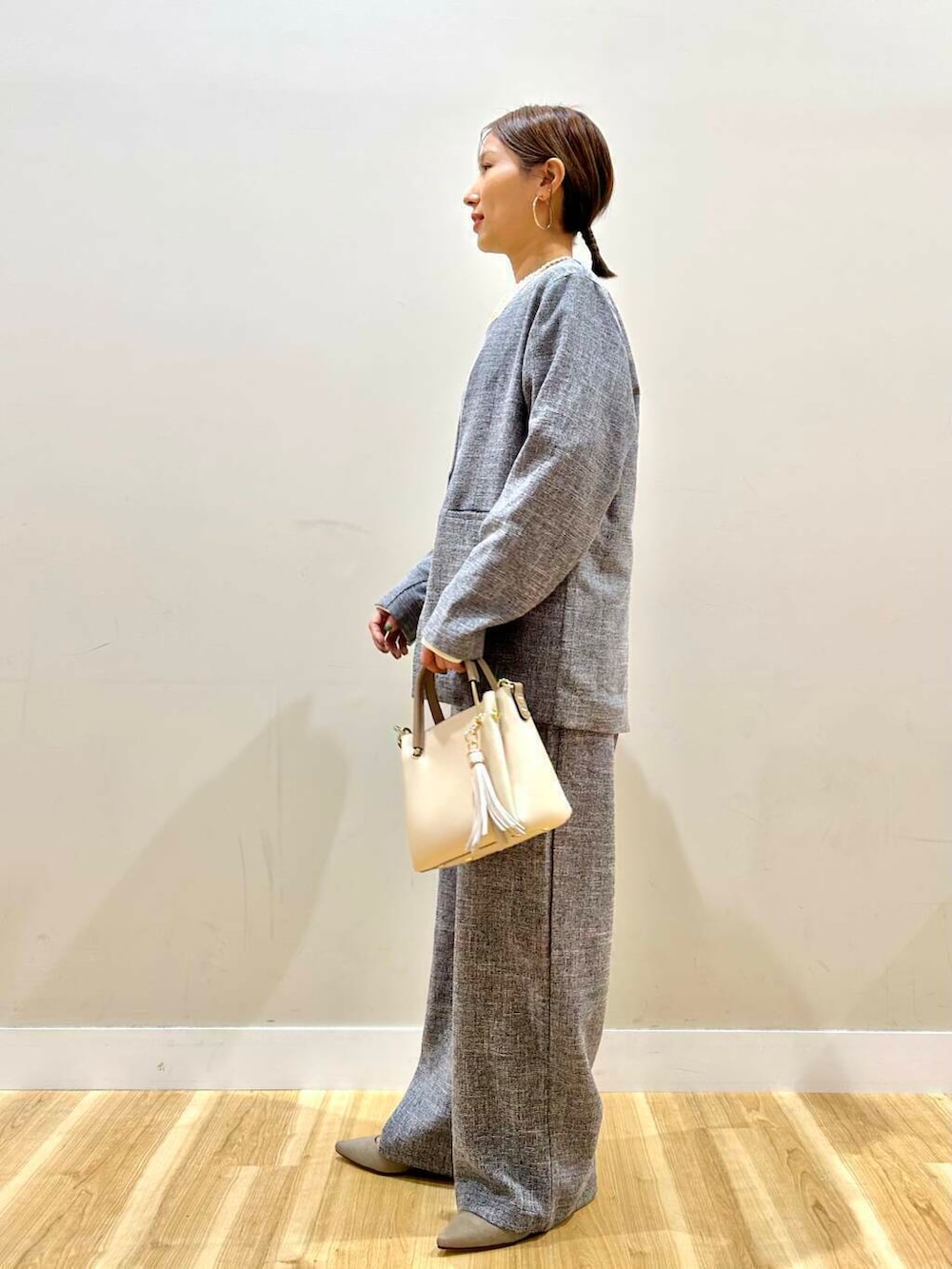 ホワイト系のトートバッグ、グレー系のパンプス、ブラック系のノーカラージャケットを着用したレディースの冬コーディネートの3枚目の写真