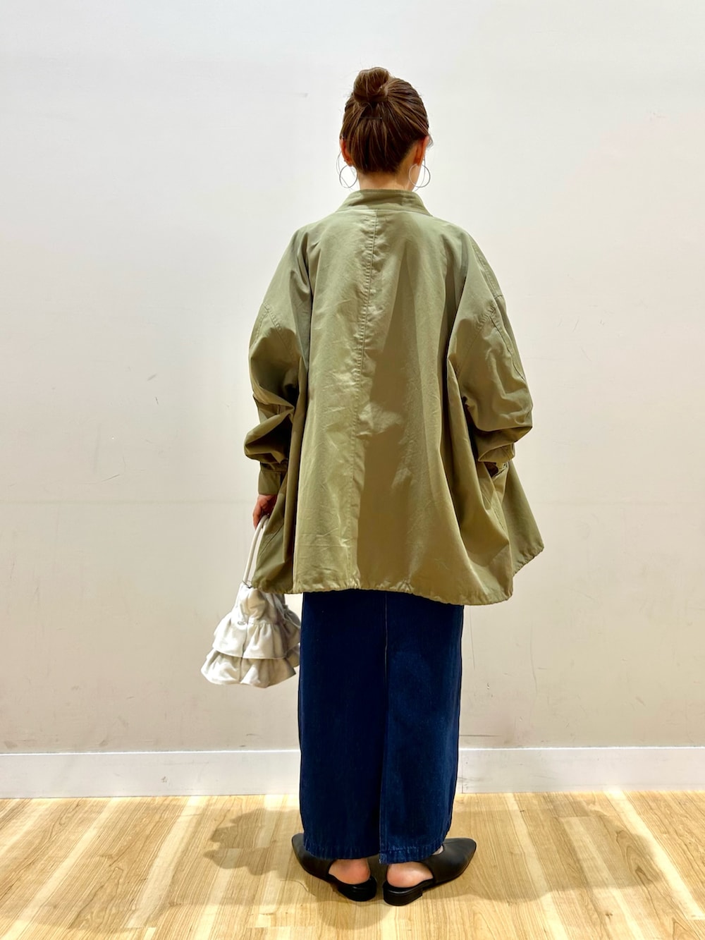 グリーン系のモッズコート、ブラック系のTシャツ/カットソー、ブルー系のワンピースを着用したレディースの春コーディネートの3枚目の写真