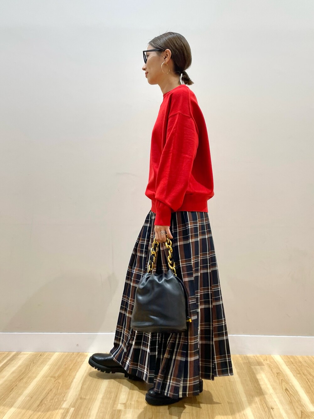レッド系のニット/セーター、ブルー系のスカートを着用したレディースの秋コーディネートの4枚目の写真