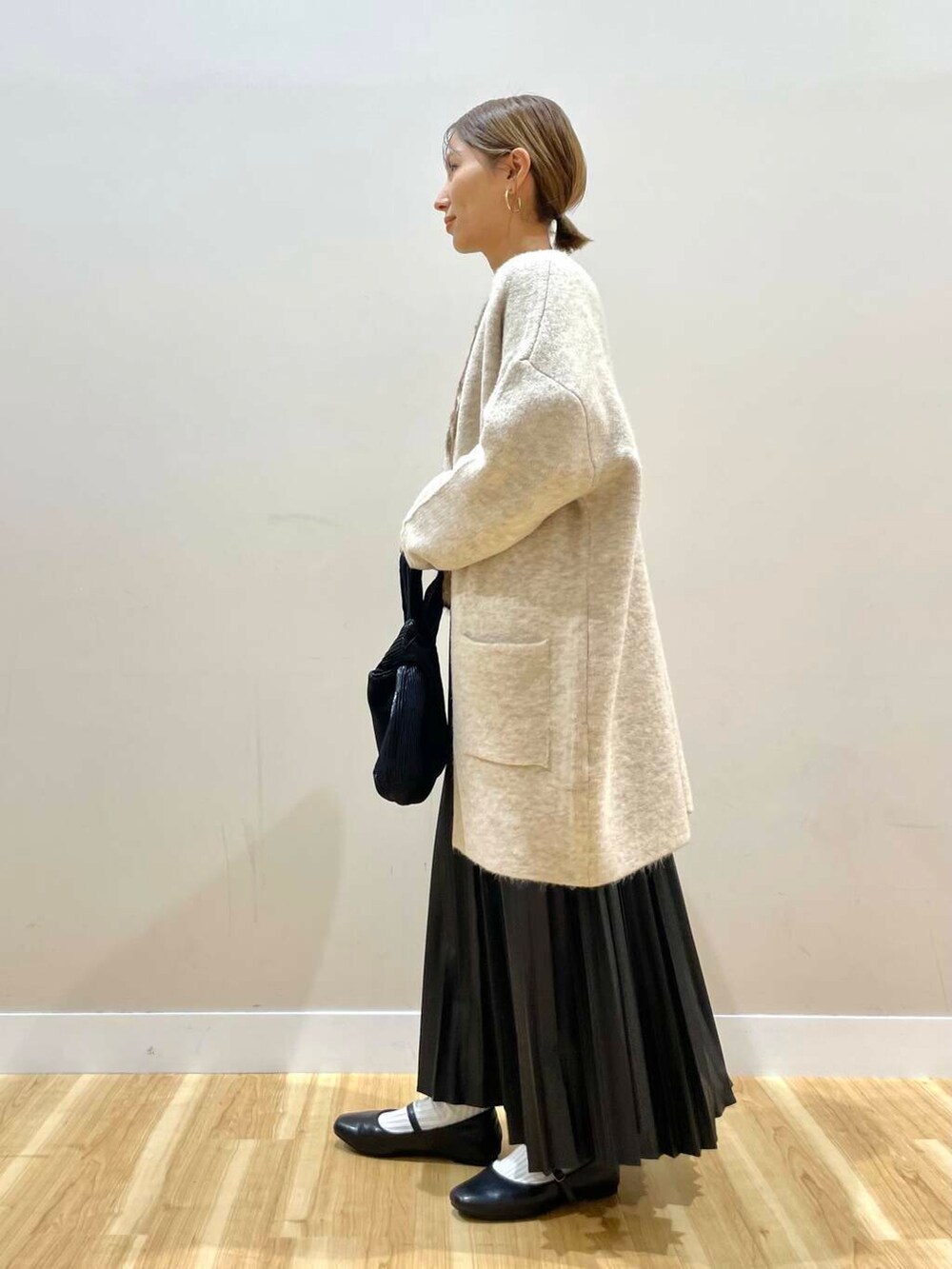 ブラック系のパンプス、ブラック系のハンドバッグ、ベージュ系のカーディガン/ボレロを着用したレディースの冬コーディネートの4枚目の写真