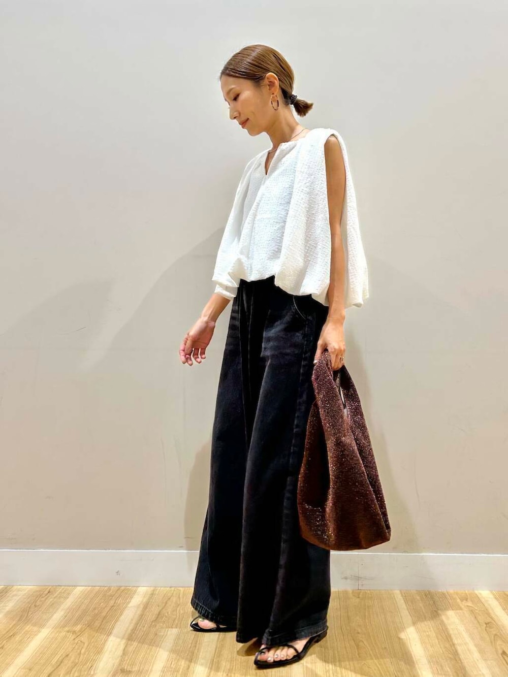 ブラウン系のトートバッグ、ブラック系のデニムパンツ、ホワイト系のシャツ/ブラウスを着用したレディースの夏コーディネートの2枚目の写真