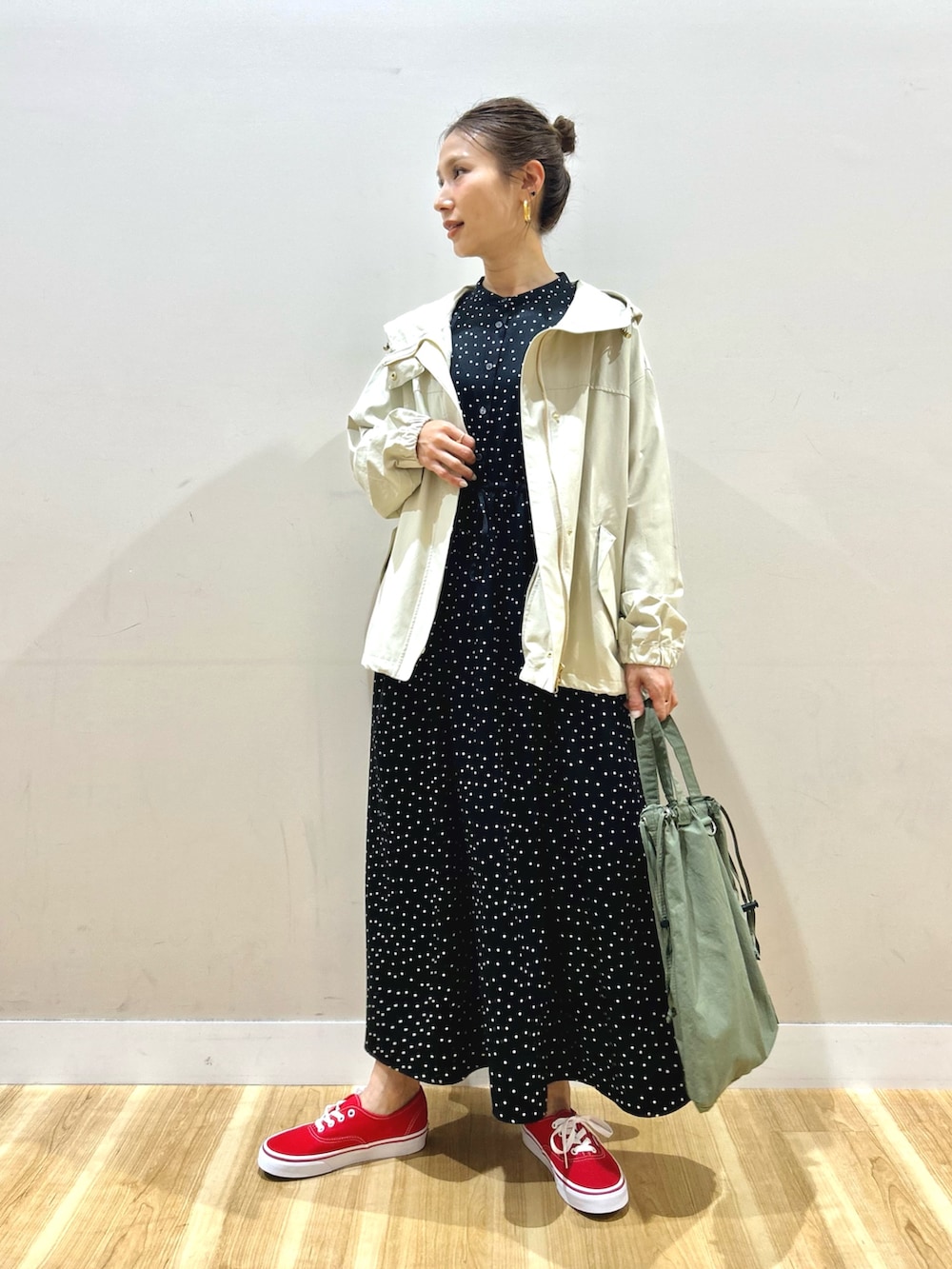ホワイト系のマウンテンパーカー、ブラック系のワンピース、グリーン系のショルダーバッグを着用したレディースの春コーディネートの2枚目の写真