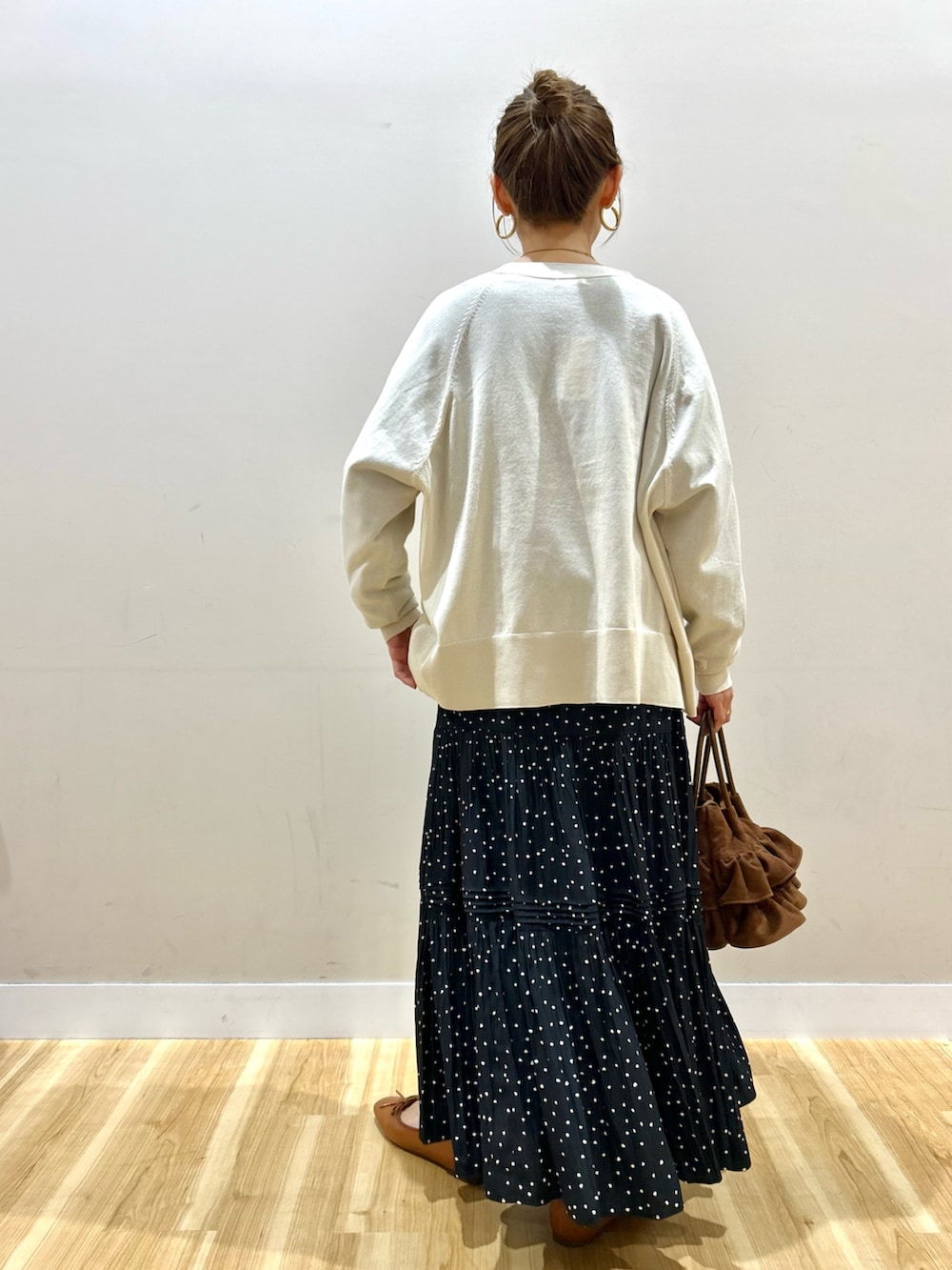 ブラック系のスウェット、ブラック系のスカート、ブラウン系のハンドバッグを着用したレディースの春コーディネートの3枚目の写真