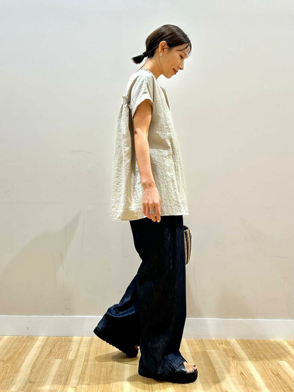 ブラック系のハンドバッグ、ブラック系のサンダル、ブルー系のデニムパンツを着用したレディースの夏コーディネートの2枚目の写真