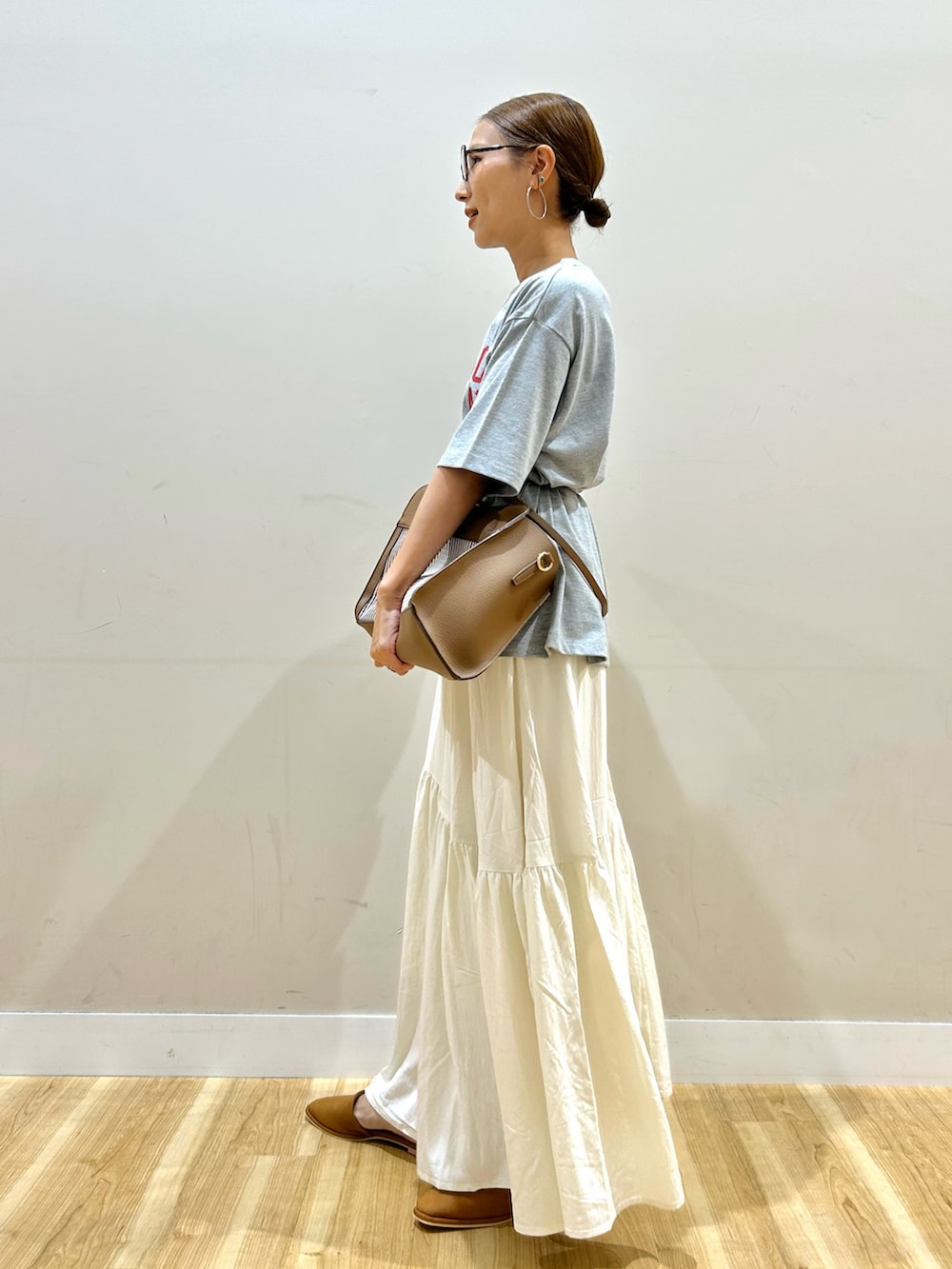 グレー系のTシャツ/カットソー、ブラウン系のショルダーバッグ、ホワイト系のスカートを着用したレディースの秋コーディネートの3枚目の写真