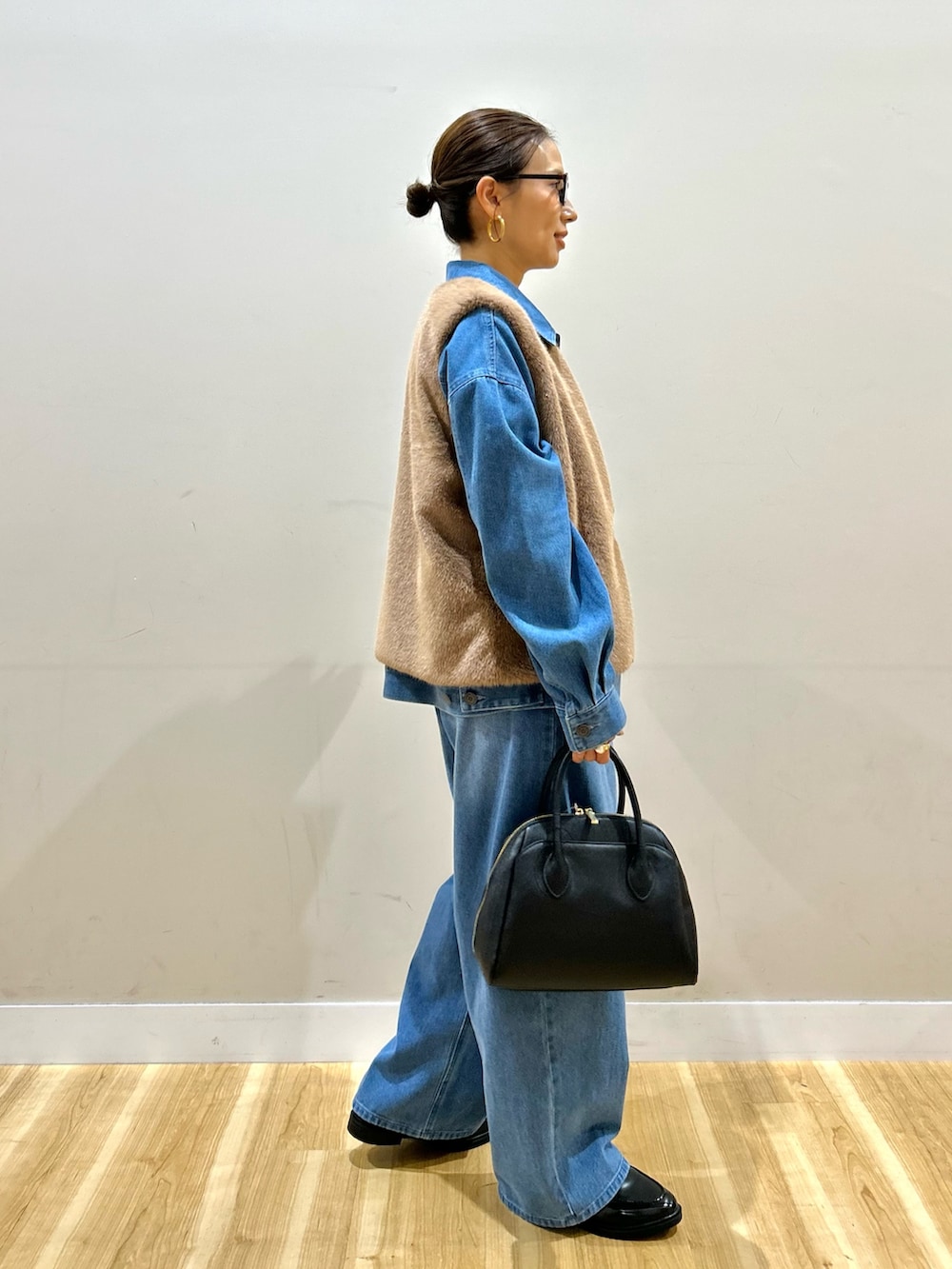 ブルー系のカバーオール、ブルー系のその他パンツ、ブラウン系のダウンベストを着用したレディースの秋コーディネートの2枚目の写真
