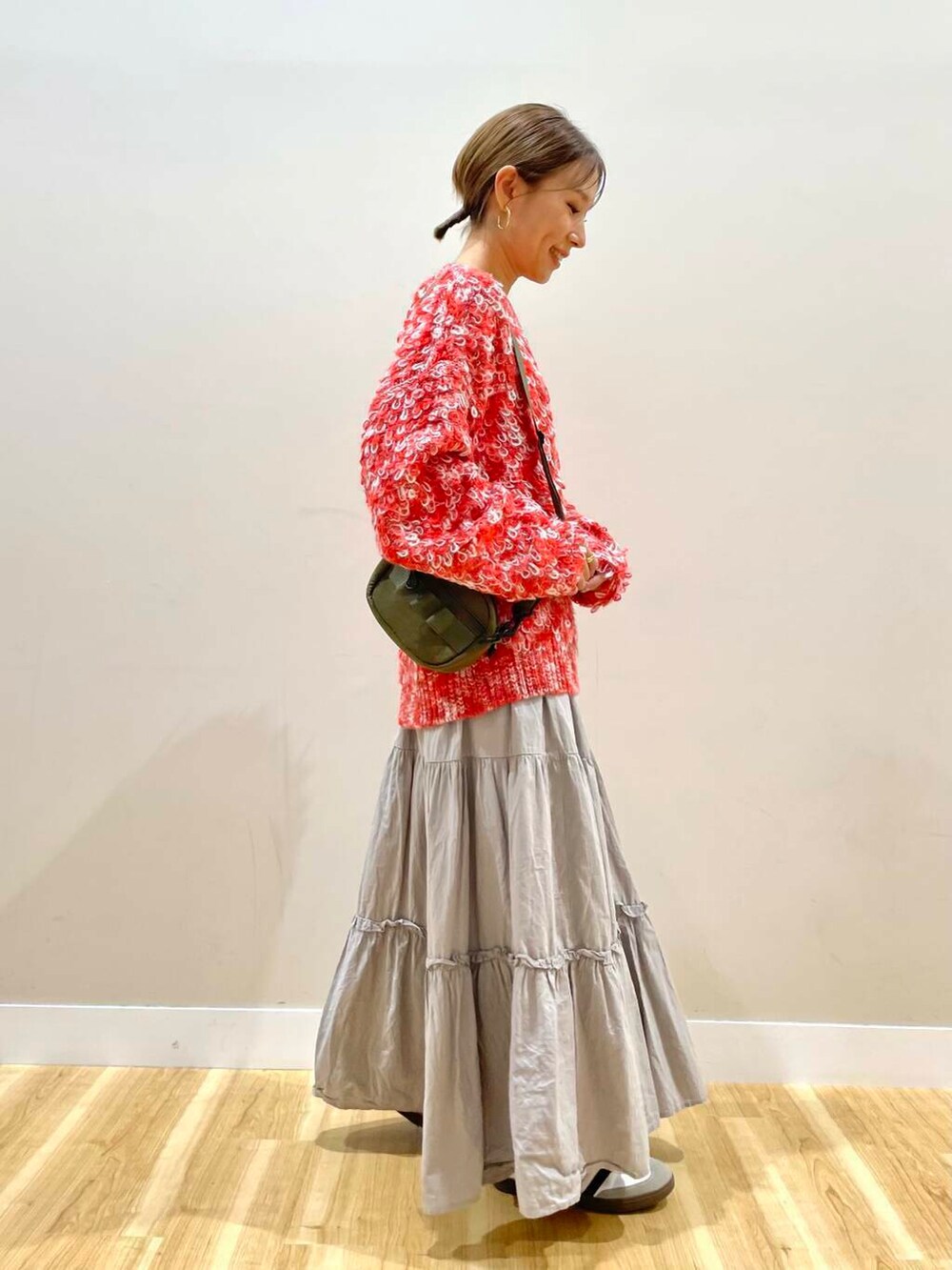 ブラック系のダウンジャケット/コート、グリーン系のショルダーバッグ、レッド系のニット/セーターを着用したレディースの冬コーディネートの6枚目の写真