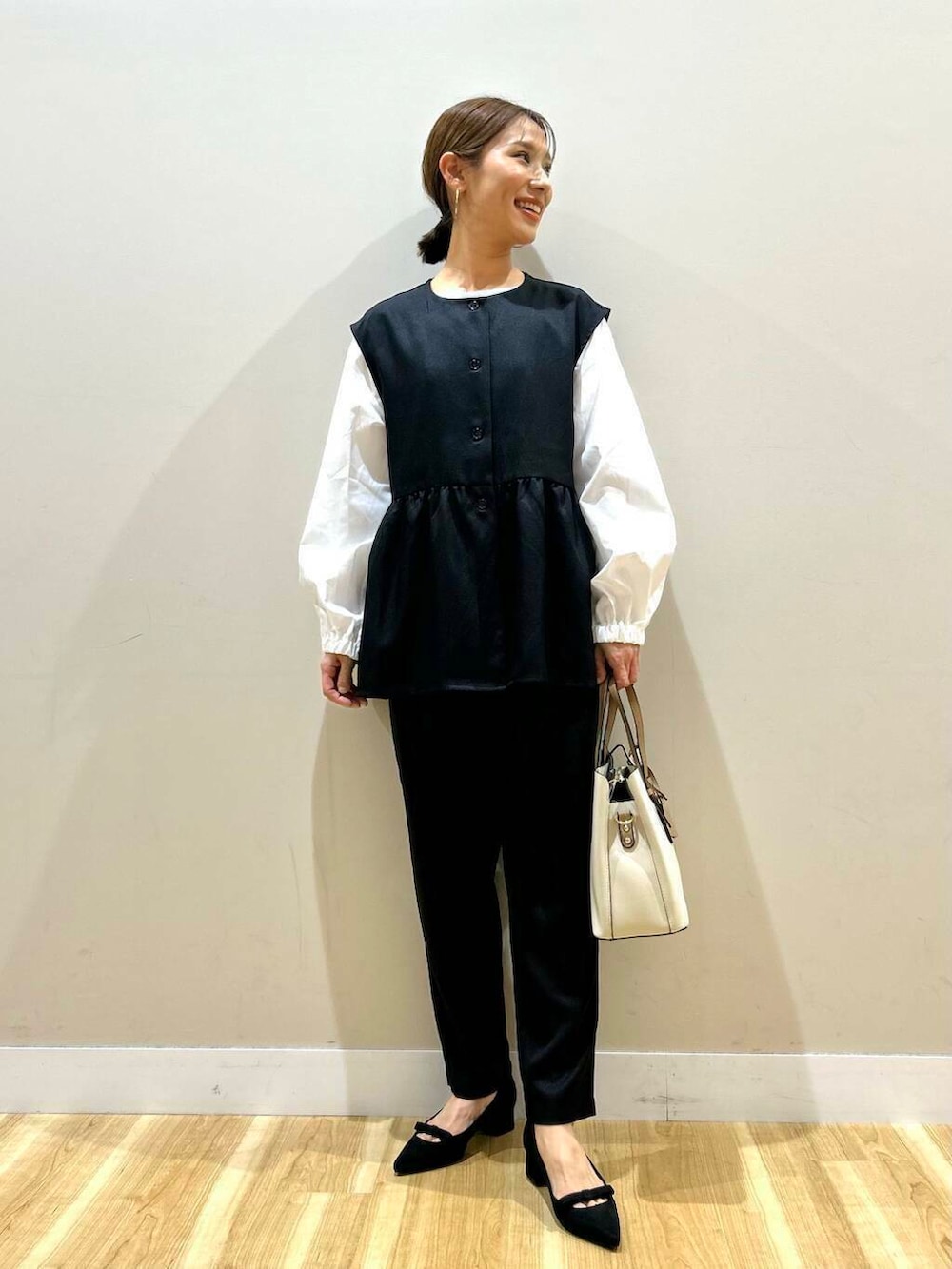 ホワイト系のトートバッグ、ブラック系のパンプス、ブラック系のセットアップを着用したレディースの冬コーディネートの4枚目の写真
