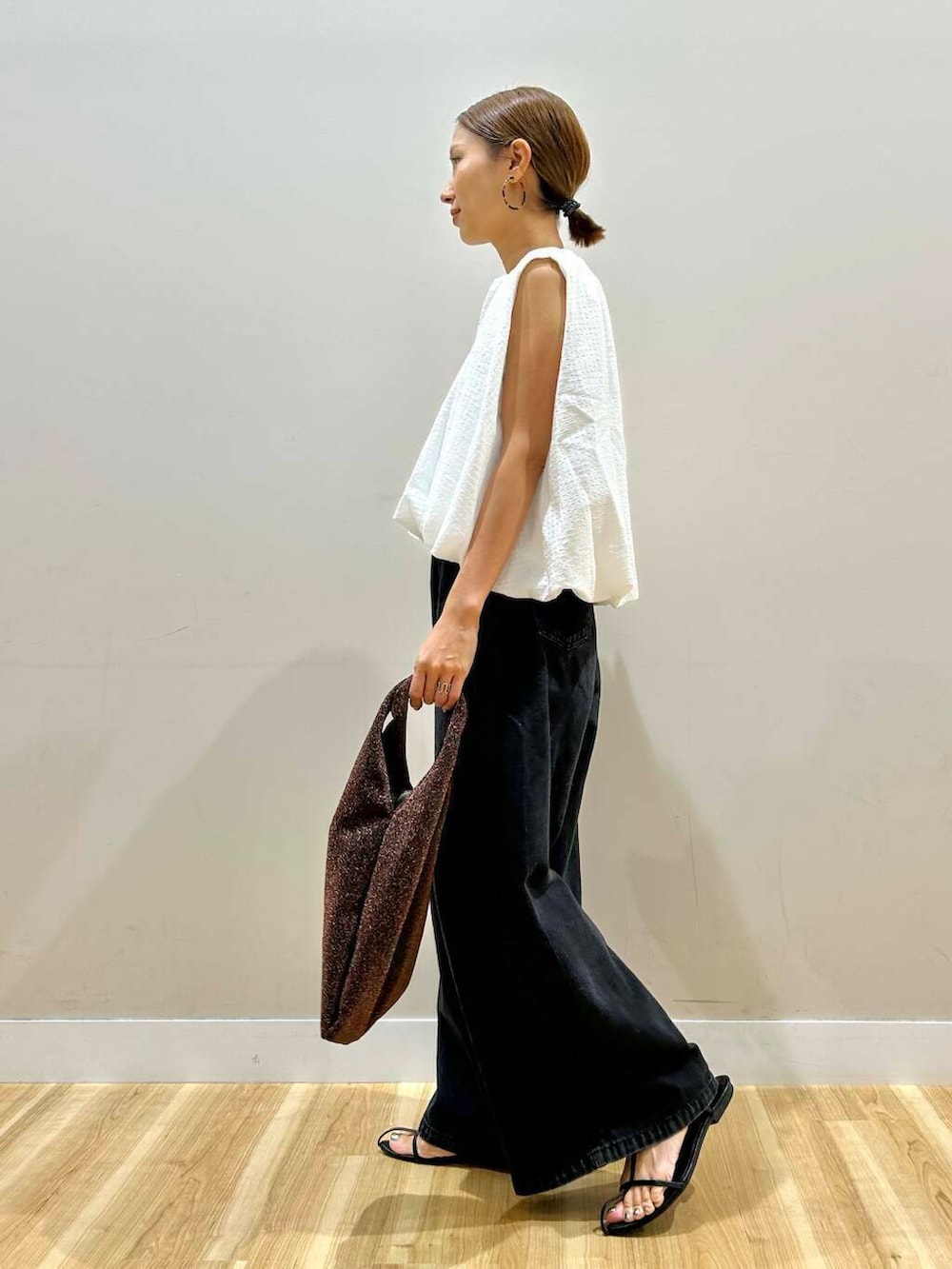 ブラウン系のトートバッグ、ブラック系のデニムパンツ、ホワイト系のシャツ/ブラウスを着用したレディースの夏コーディネートの3枚目の写真