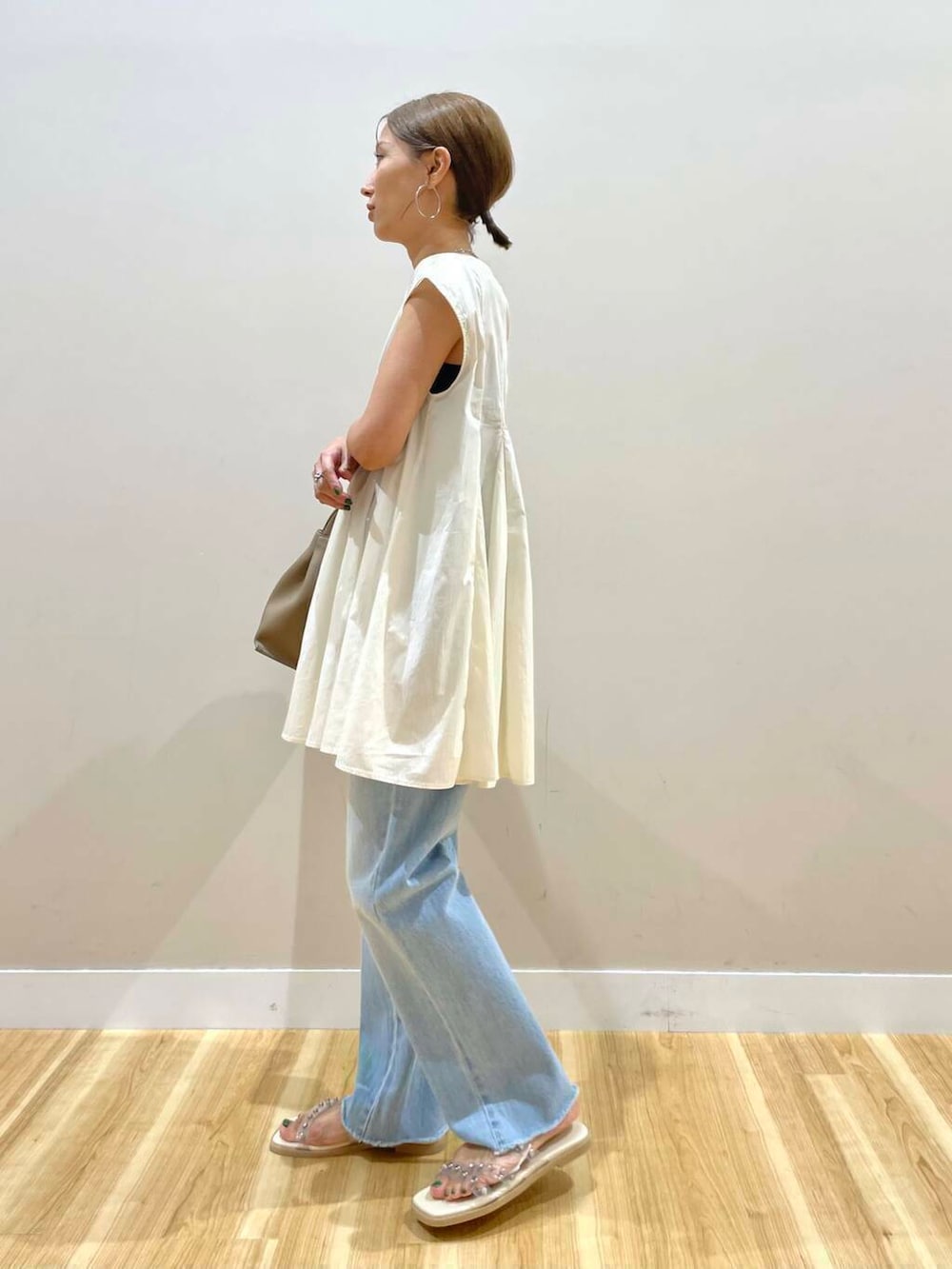 ホワイト系のサンダル、ブルー系のデニムパンツ、ベージュ系のハンドバッグを着用したレディースの夏コーディネートの3枚目の写真