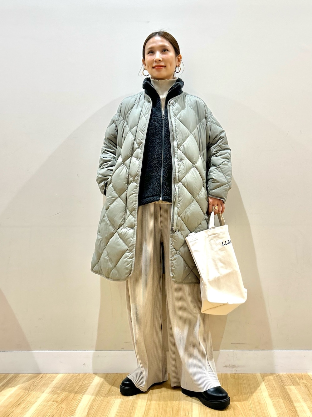 グレー系のベスト、グリーン系のダウンジャケット/コート、ホワイト系のニット/セーターを着用したレディースの冬コーディネートの7枚目の写真
