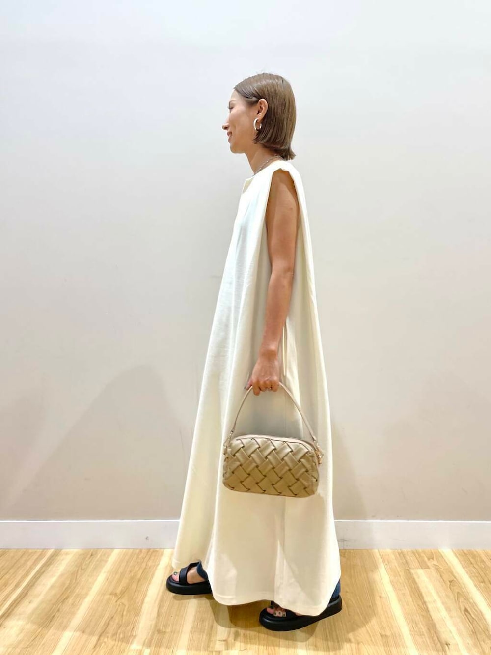 ブラック系のサンダル、ホワイト系のワンピース、ベージュ系のショルダーバッグを着用したレディースの夏コーディネートの4枚目の写真