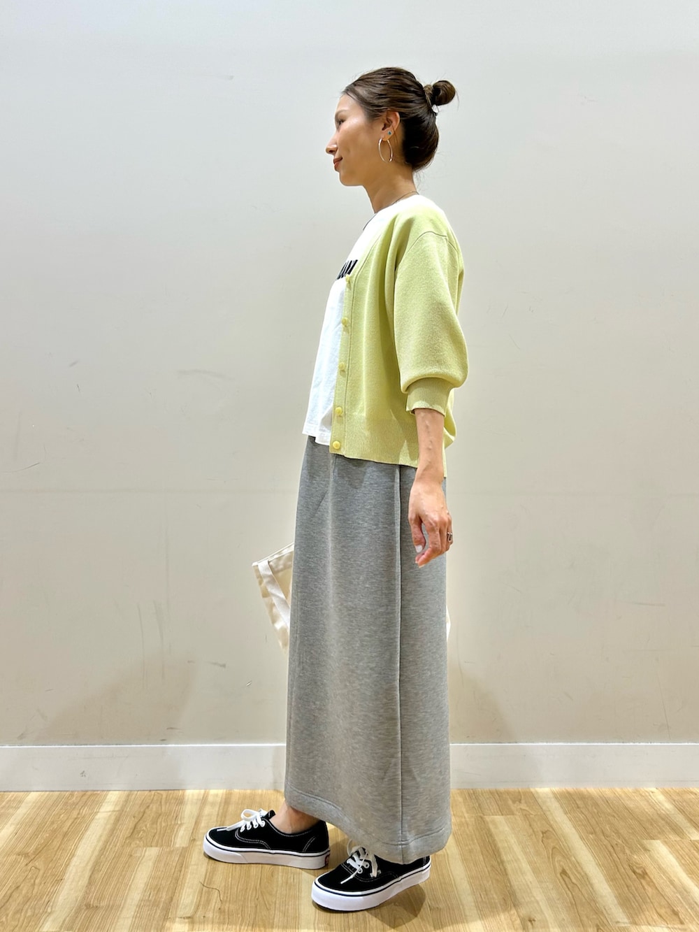 イエロー系のカーディガン/ボレロ、ホワイト系のTシャツ/カットソー、グレー系のスカートを着用したレディースの春コーディネートの2枚目の写真