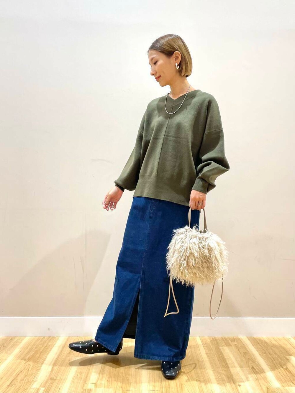 ベージュ系のショルダーバッグ、ブラック系のパンプス、ブルー系のスカートを着用したレディースの秋コーディネートの2枚目の写真