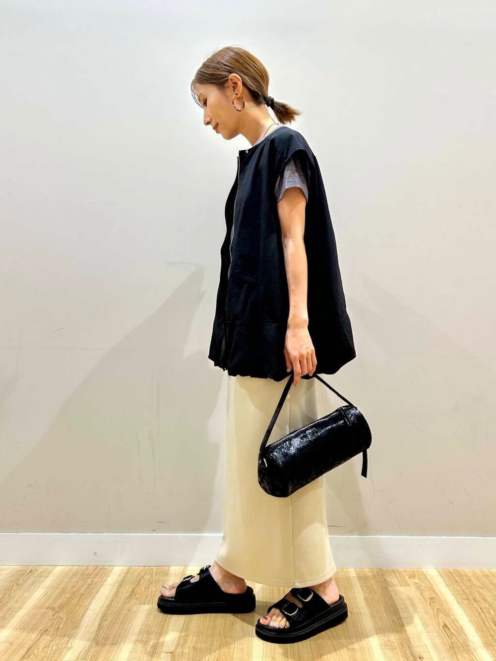 ブラック系のハンドバッグ、グレー系のTシャツ/カットソー、グリーン系のスカートを着用したレディースの夏コーディネートの2枚目の写真