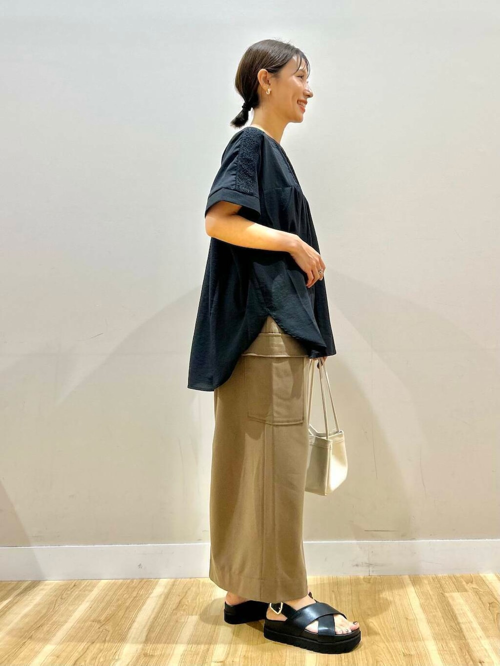 ブラック系のシャツ/ブラウス、ホワイト系のハンドバッグ、ブラック系のサンダルを着用したレディースの夏コーディネートの4枚目の写真