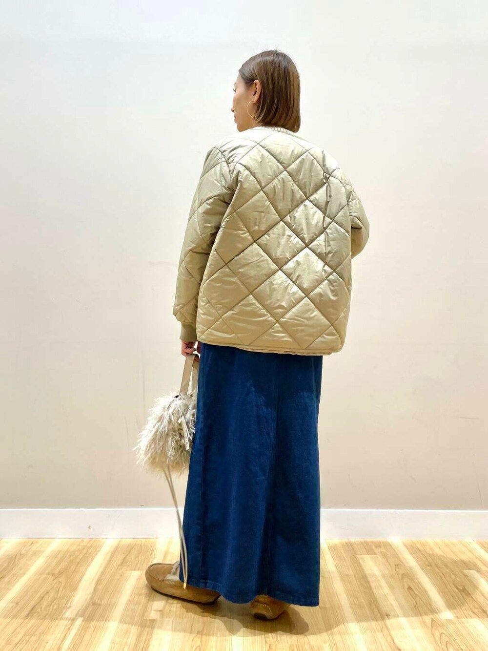 ベージュ系のショルダーバッグ、ブルー系のスカート、ベージュ系のダウンジャケット/コートを着用したレディースの秋コーディネートの5枚目の写真