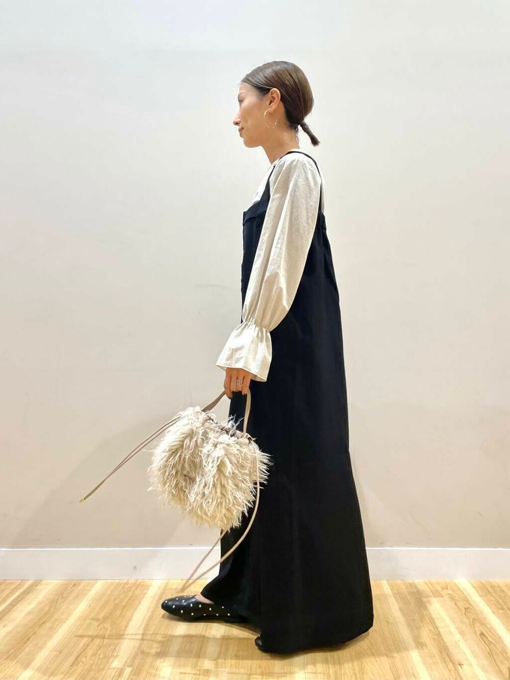 ベージュ系のショルダーバッグ、ブラック系のパンプス、ブラック系のジャンパースカートを着用したレディースの秋コーディネートの2枚目の写真