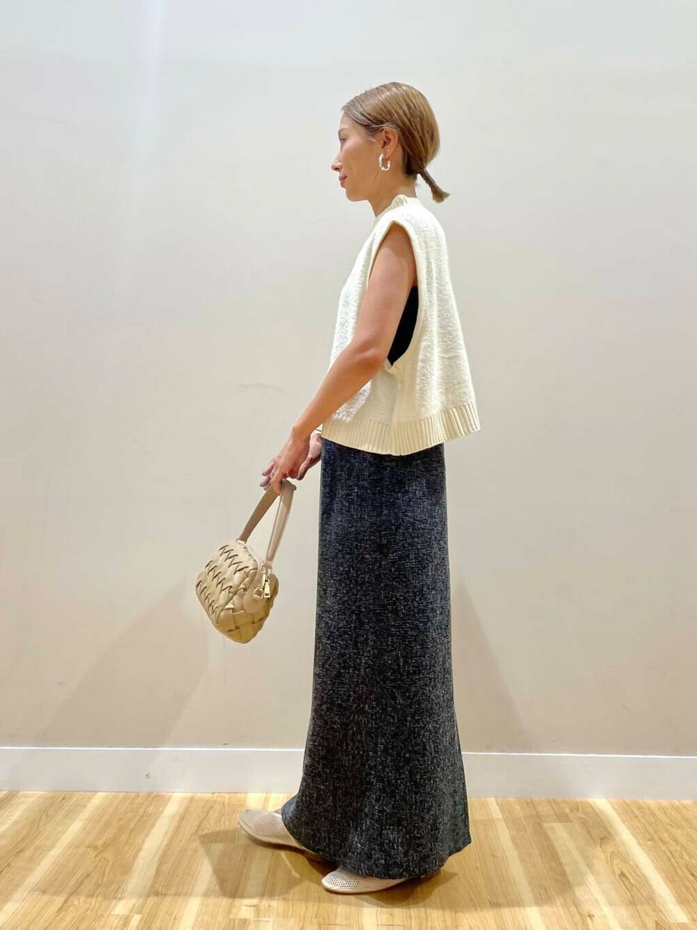 ベージュ系のショルダーバッグ、ブラック系のスカート、ホワイト系のニット/セーターを着用したレディースの夏コーディネートの2枚目の写真