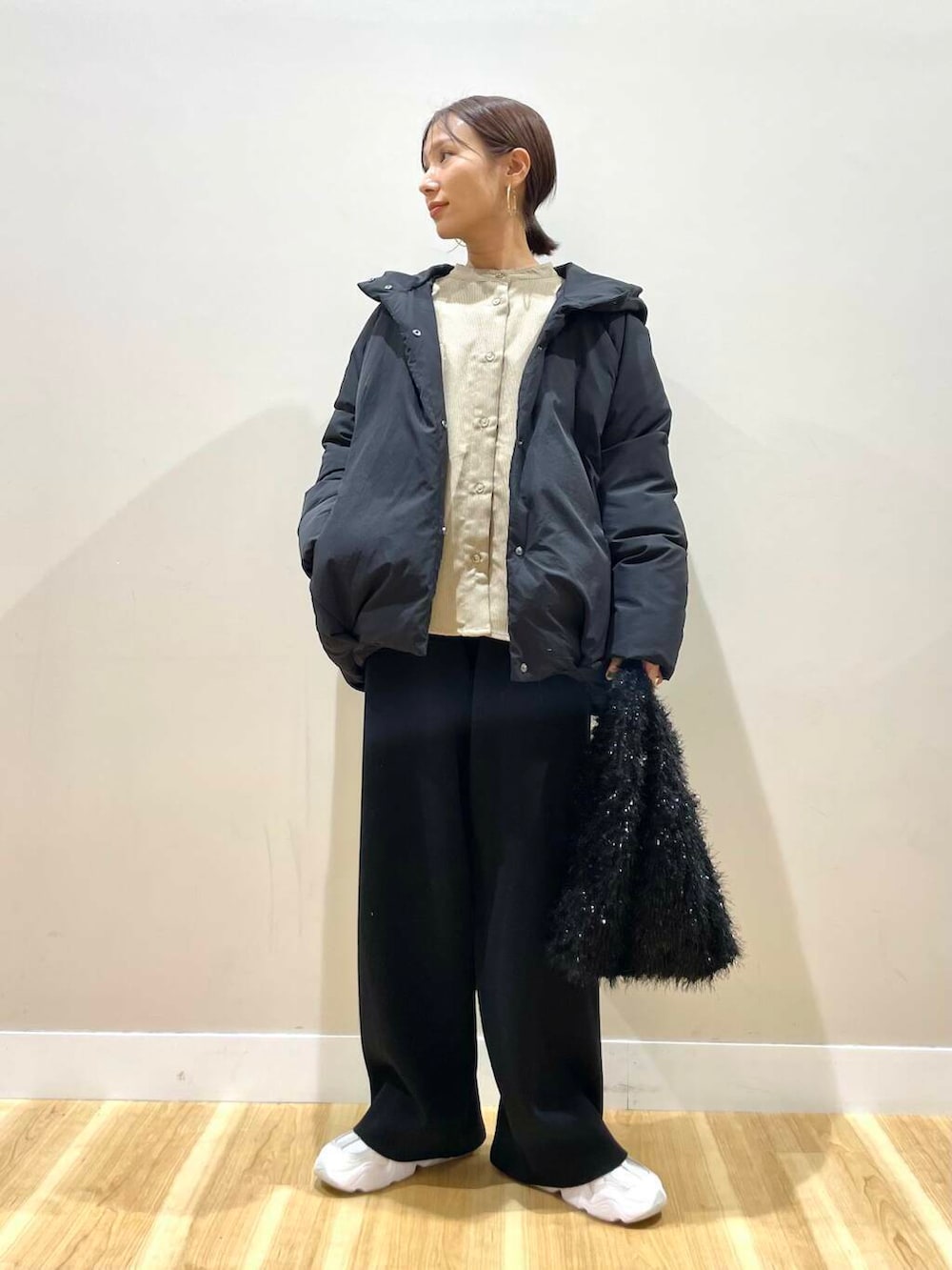 ホワイト系のスニーカー、ベージュ系のTシャツ/カットソー、ブラック系のダウンジャケット/コートを着用したレディースの冬コーディネートの2枚目の写真