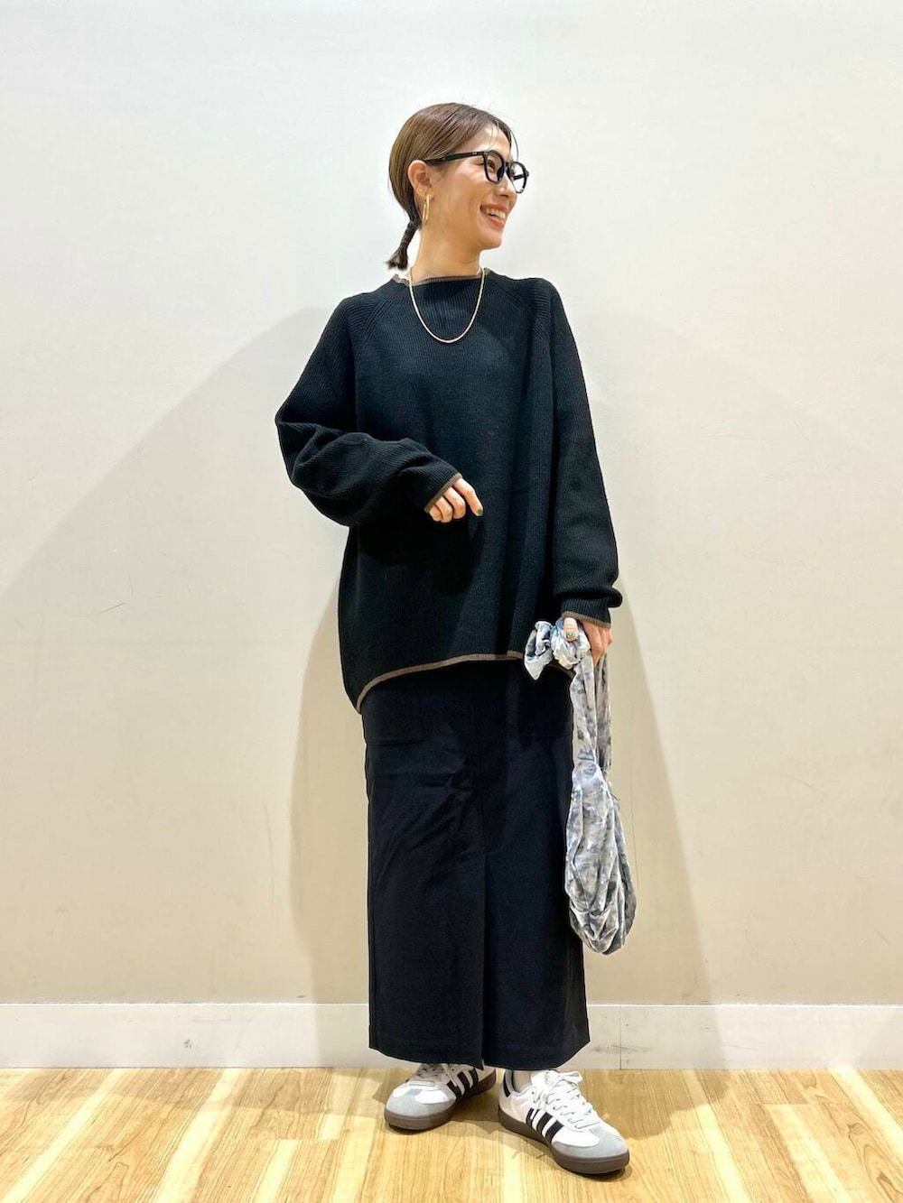 グレー系のハンドバッグ、ブラック系のニット/セーター、ブラック系のスカートを着用したレディースの冬コーディネートの6枚目の写真