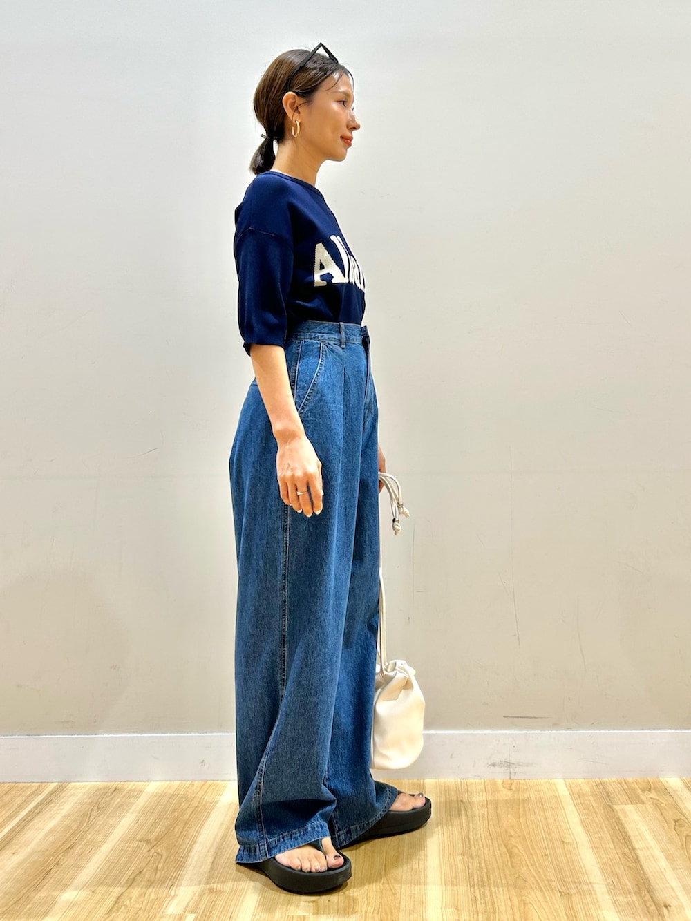 ブルー系のニット/セーター、ブルー系のデニムパンツ、ホワイト系のショルダーバッグを着用したレディースの夏コーディネートの5枚目の写真