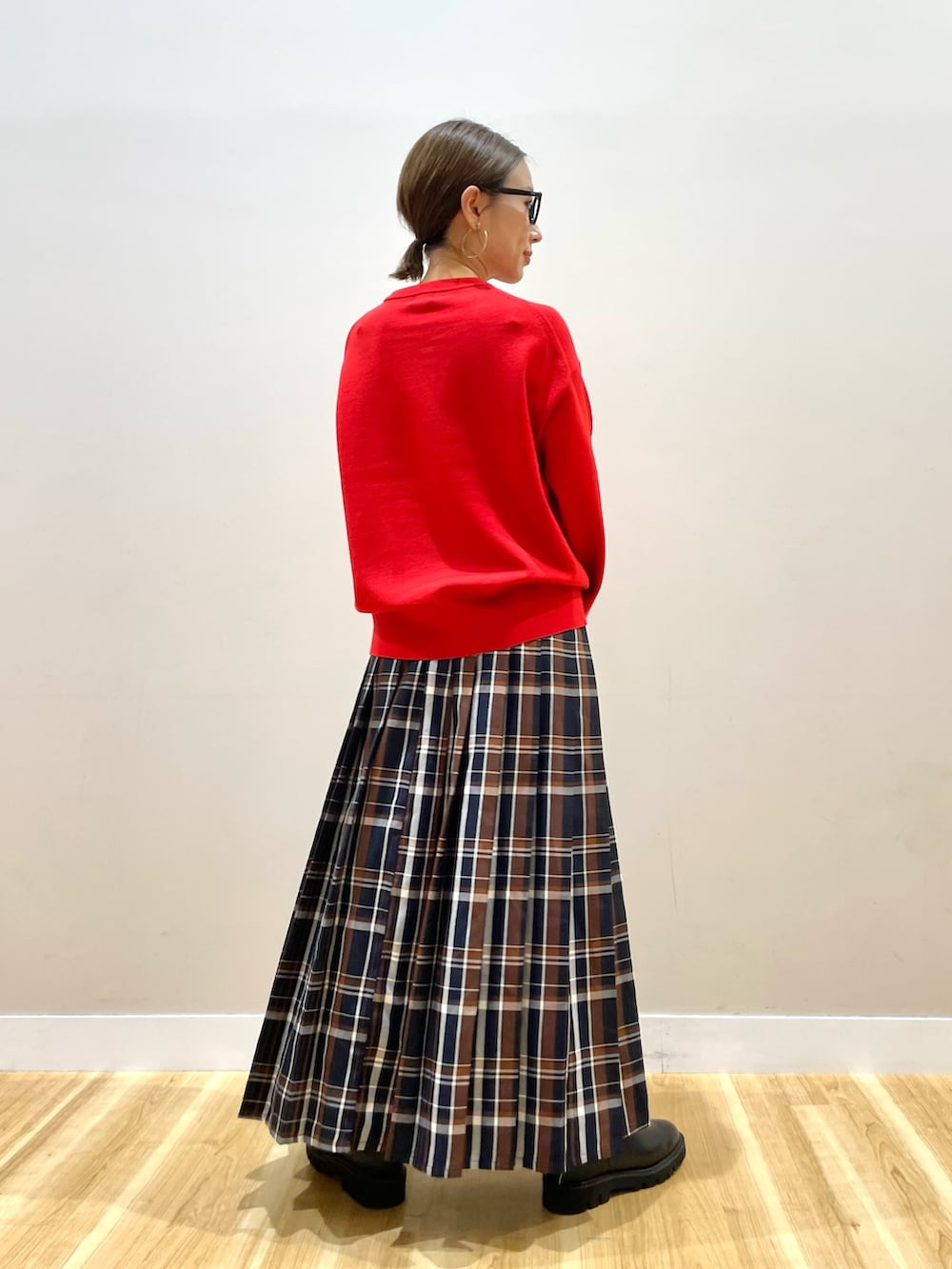 レッド系のニット/セーター、ブルー系のスカートを着用したレディースの秋コーディネートの3枚目の写真