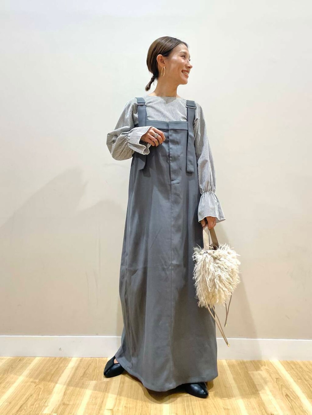 ベージュ系のショルダーバッグ、グレー系のジャンパースカートを着用したレディースの秋コーディネートの6枚目の写真