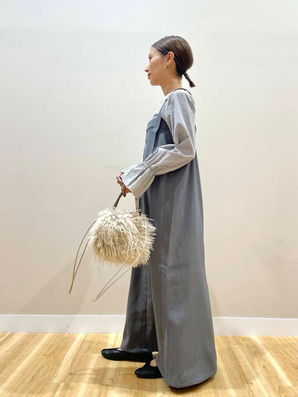 ベージュ系のショルダーバッグ、グレー系のジャンパースカートを着用したレディースの秋コーディネートの5枚目の写真