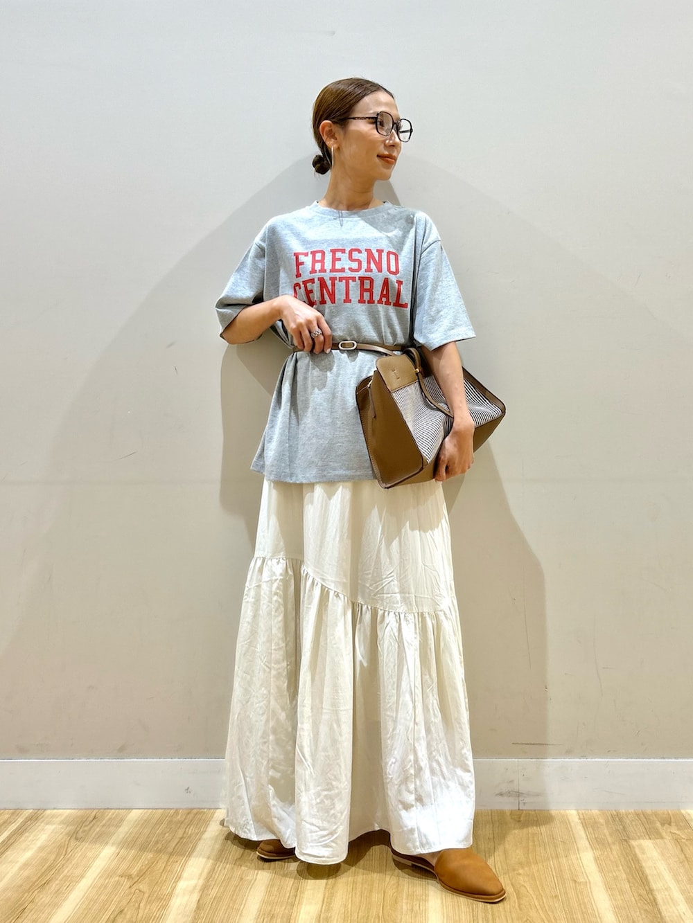 グレー系のTシャツ/カットソー、ブラウン系のショルダーバッグ、ホワイト系のスカートを着用したレディースの秋コーディネートの2枚目の写真