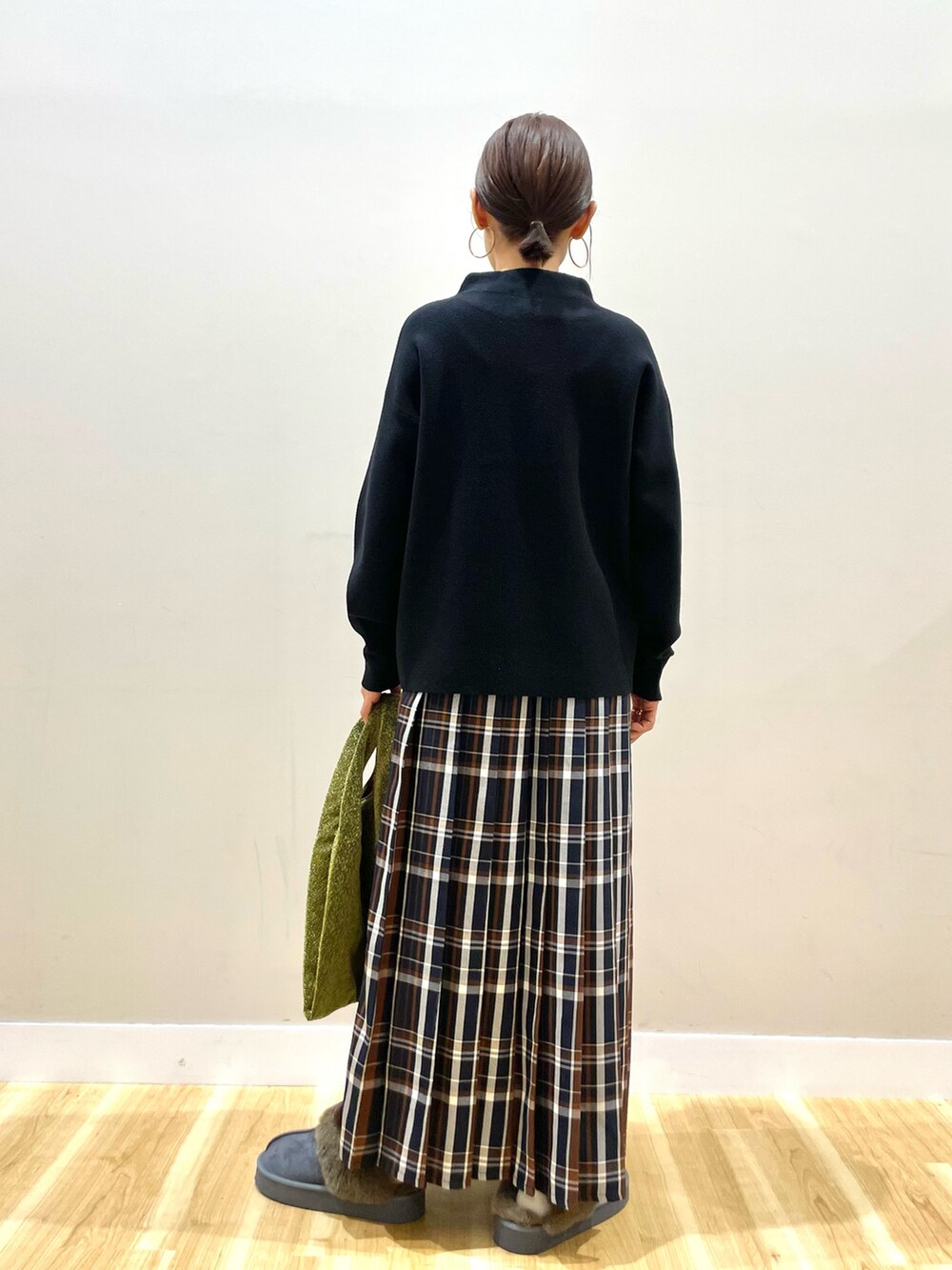 グレー系のノーカラーコート、ブラック系のニット/セーター、ブルー系のスカートを着用したレディースの冬コーディネートの6枚目の写真