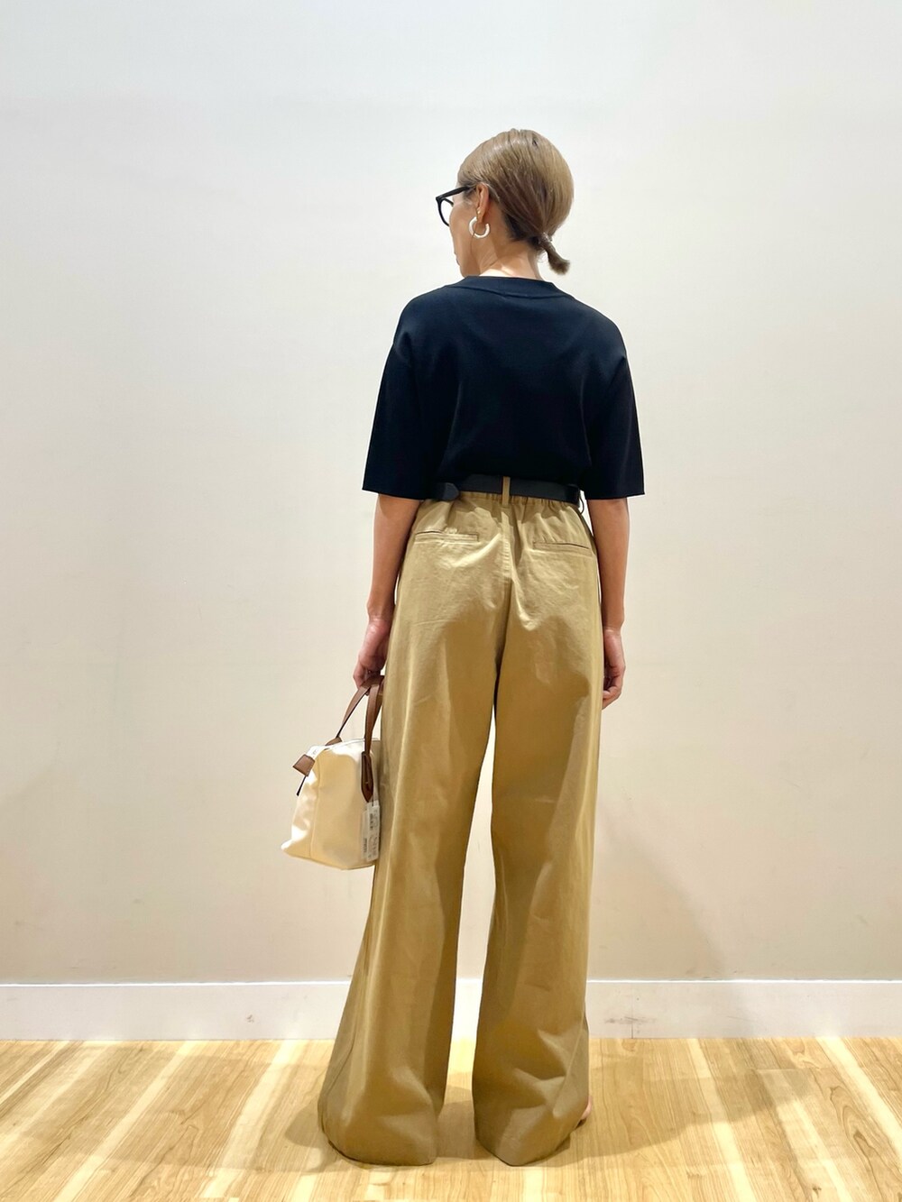 ブラック系のニット/セーター、イエロー系のチノパンツを着用したレディースの夏コーディネートの3枚目の写真