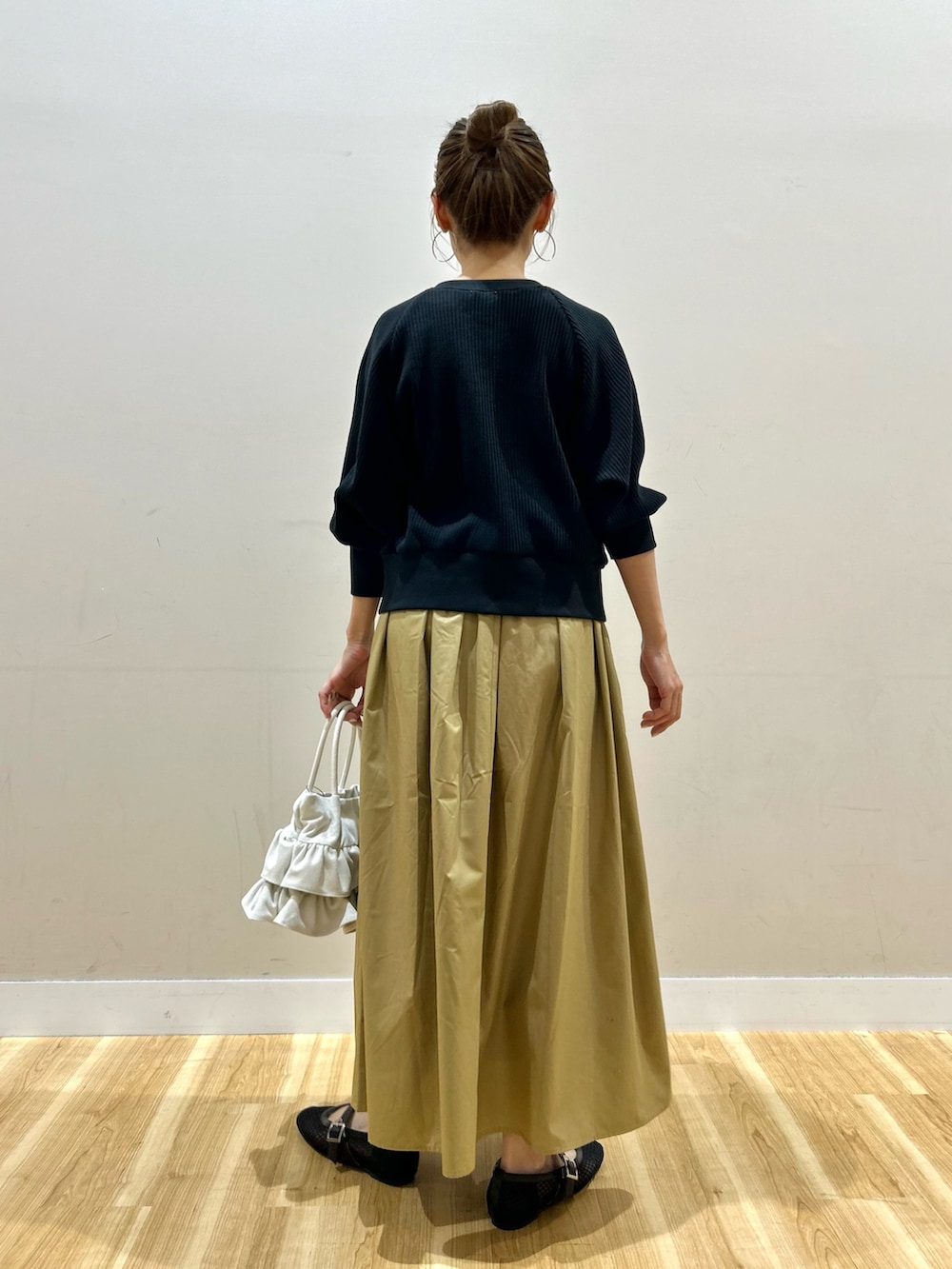 ブラック系のカーディガン/ボレロ、イエロー系のスカート、ホワイト系のハンドバッグを着用したレディースの春コーディネートの3枚目の写真