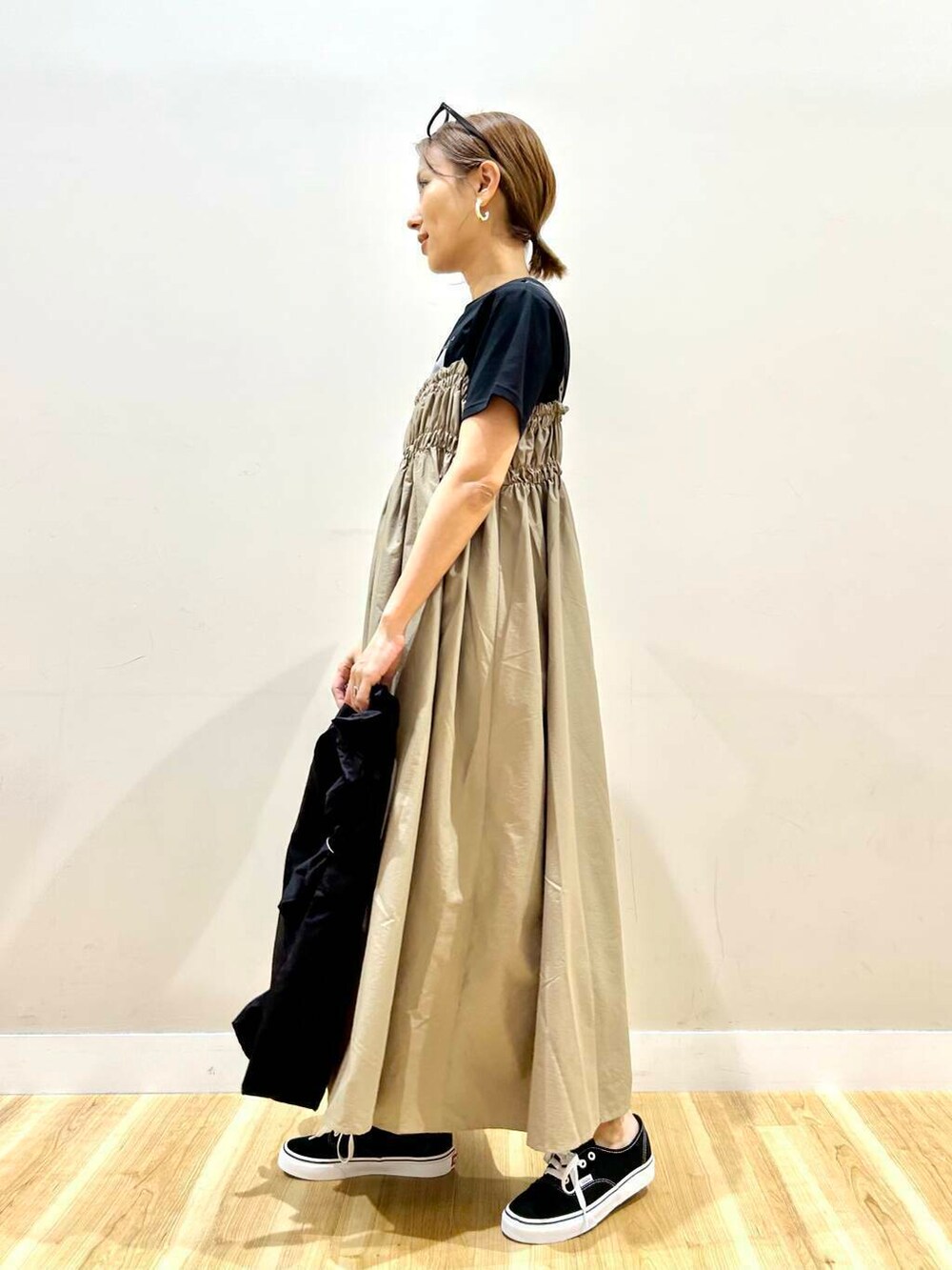 ブラック系のスニーカー、ブラック系のトートバッグ、ベージュ系のワンピースを着用したレディースの春コーディネートの3枚目の写真