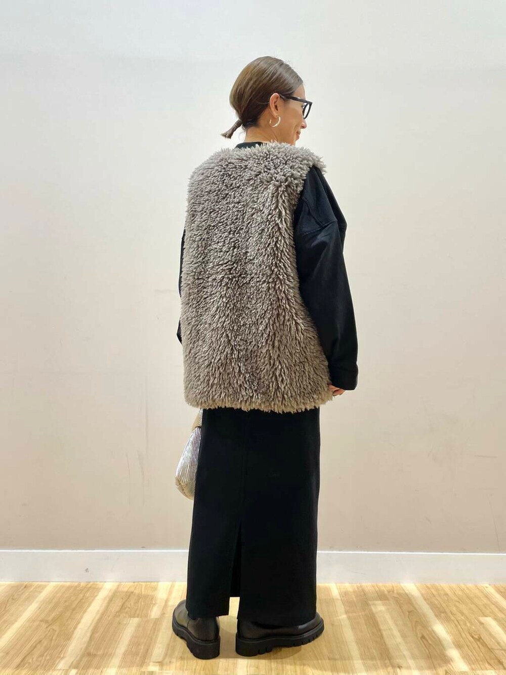 ブラック系のブーツ、グレー系のベスト、ゴールド系のハンドバッグを着用したレディースの秋コーディネートの4枚目の写真