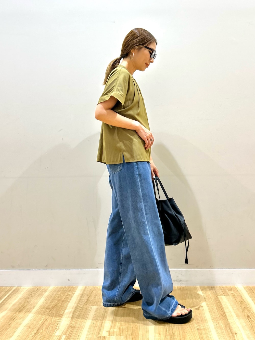 イエロー系のシャツ/ブラウス、ブルー系のデニムパンツ、ブラック系のショルダーバッグを着用したレディースの夏コーディネートの2枚目の写真