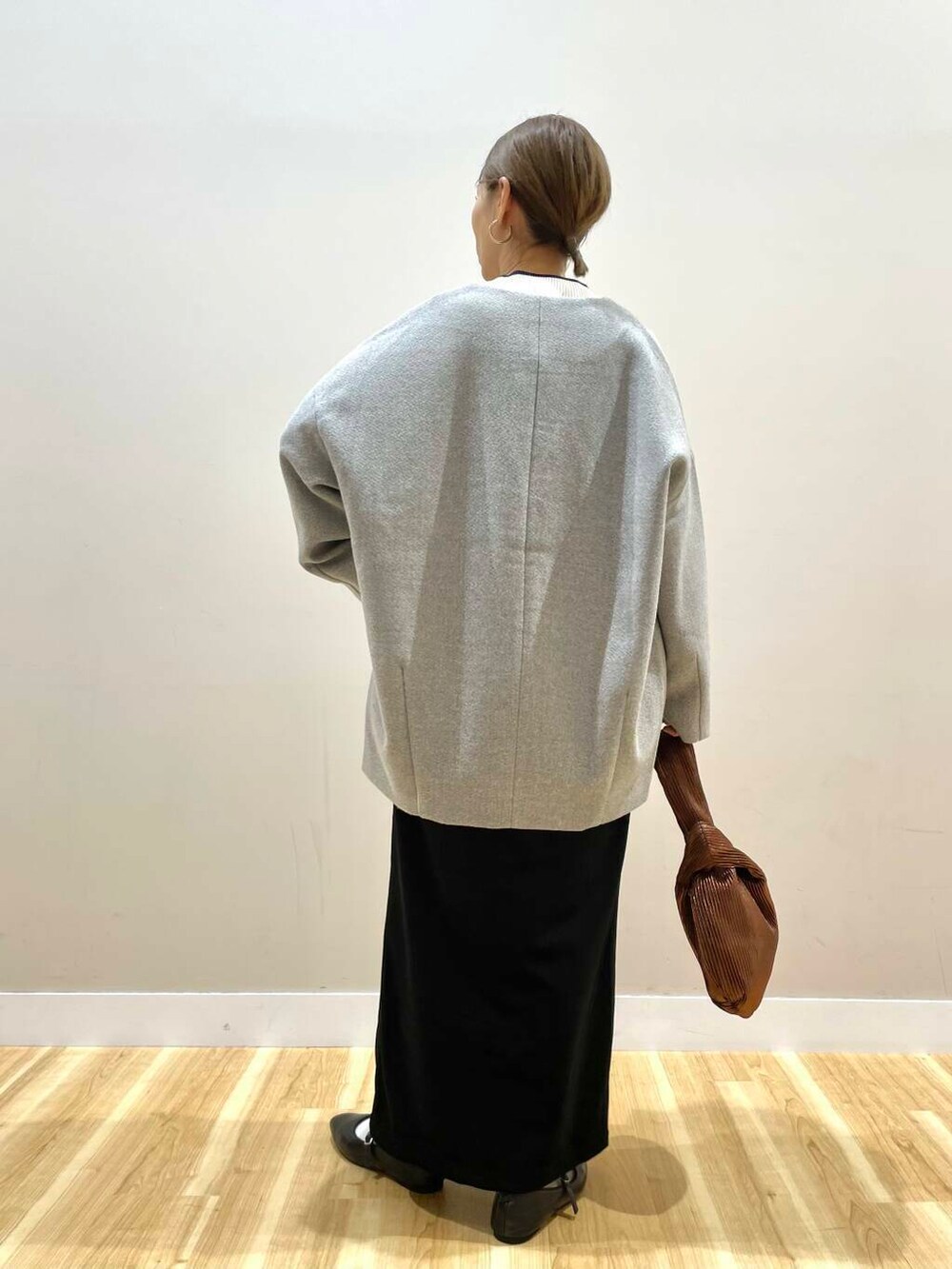 ブラック系のパンプス、ブラウン系のハンドバッグ、ホワイト系のニット/セーターを着用したレディースの冬コーディネートの4枚目の写真