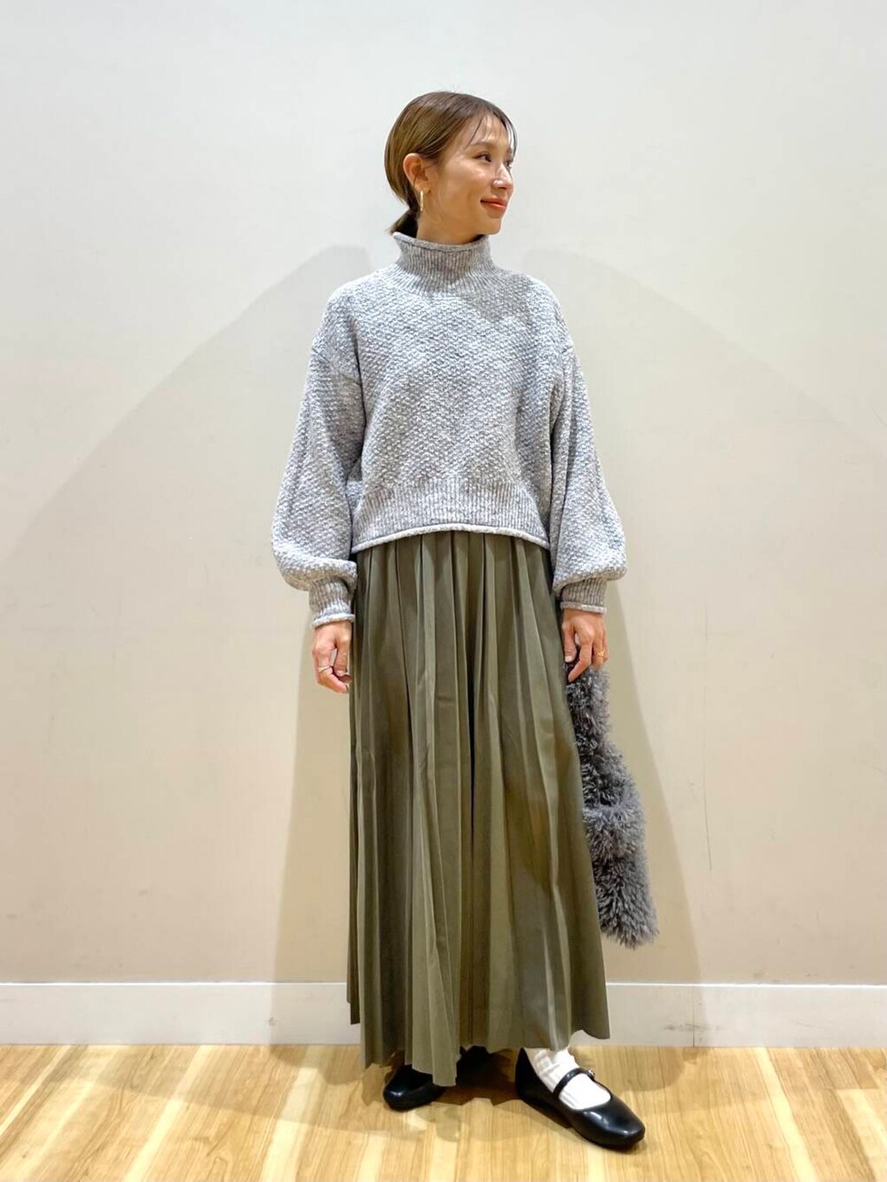 ブラック系のパンプス、グリーン系のスカート、グレー系のハンドバッグを着用したレディースの冬コーディネートの7枚目の写真