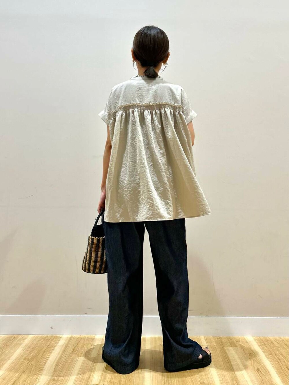 ブラック系のハンドバッグ、ブラック系のサンダル、ブルー系のデニムパンツを着用したレディースの夏コーディネートの3枚目の写真