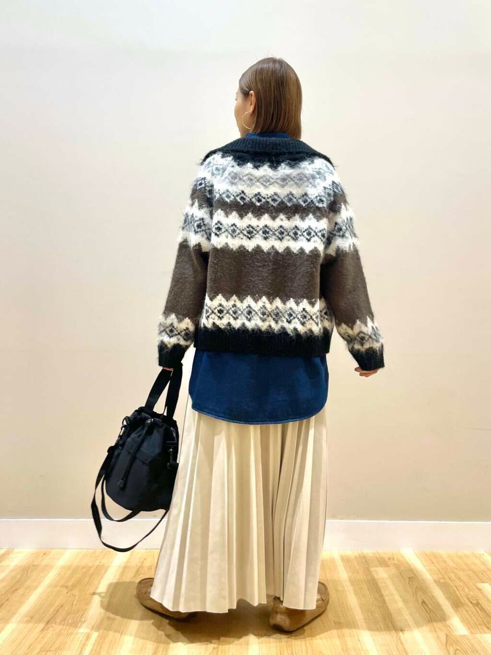 ブラック系のショルダーバッグ、ベージュ系のスカート、ブラウン系のカーディガン/ボレロを着用したレディースの秋コーディネートの3枚目の写真