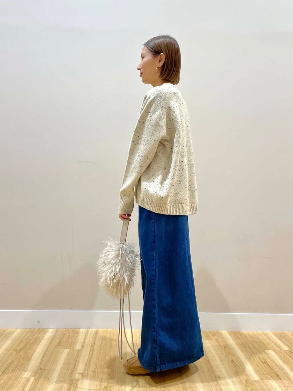 ベージュ系のショルダーバッグ、ブルー系のスカート、ベージュ系のダウンジャケット/コートを着用したレディースの秋コーディネートの7枚目の写真