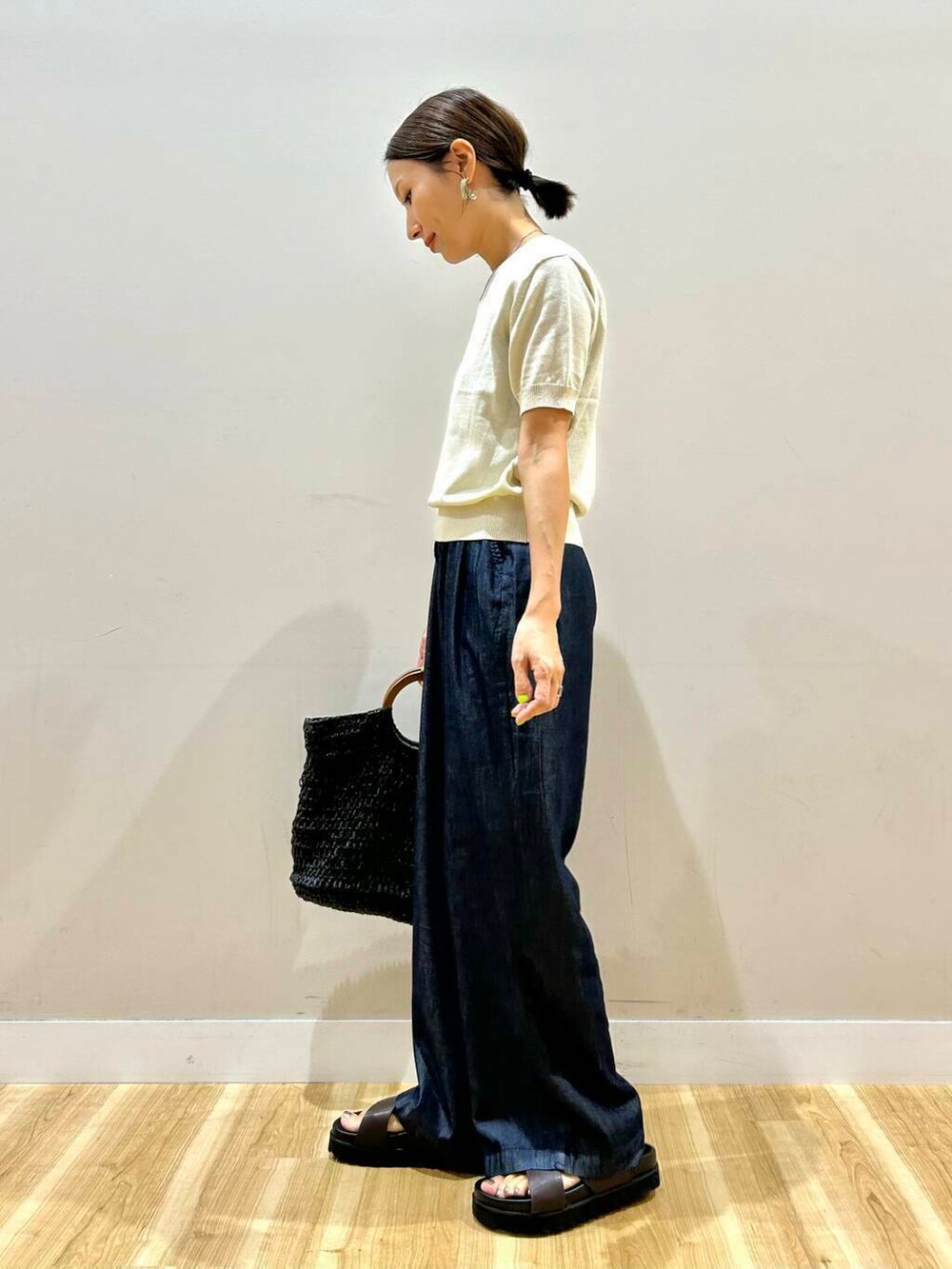 ブラック系のトートバッグ、ブラウン系のサンダル、ホワイト系のニット/セーターを着用したレディースの夏コーディネートの4枚目の写真