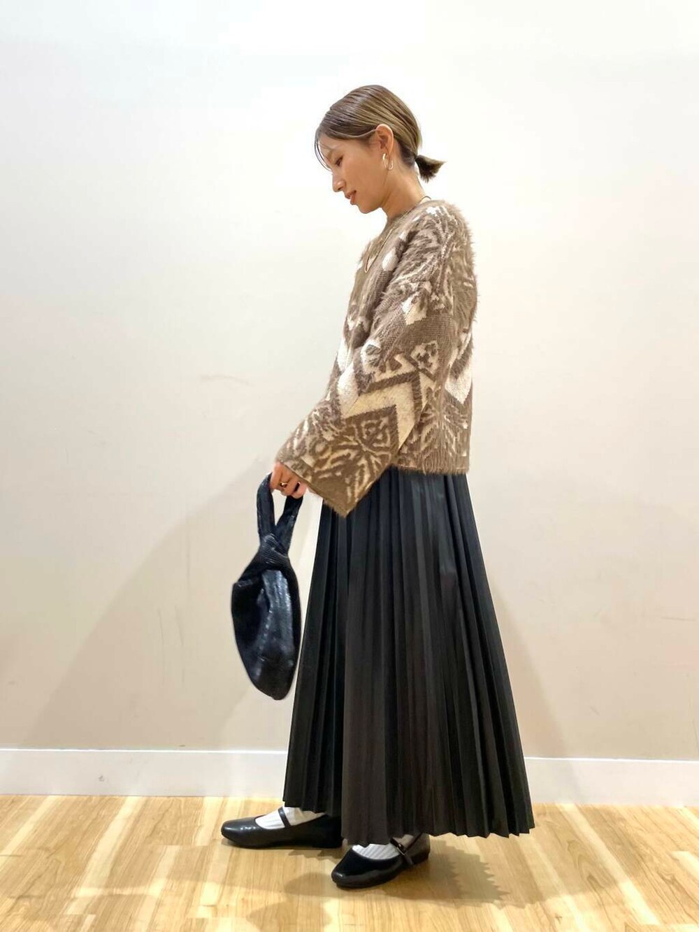 ブラック系のパンプス、ブラック系のハンドバッグ、ベージュ系のカーディガン/ボレロを着用したレディースの冬コーディネートの9枚目の写真