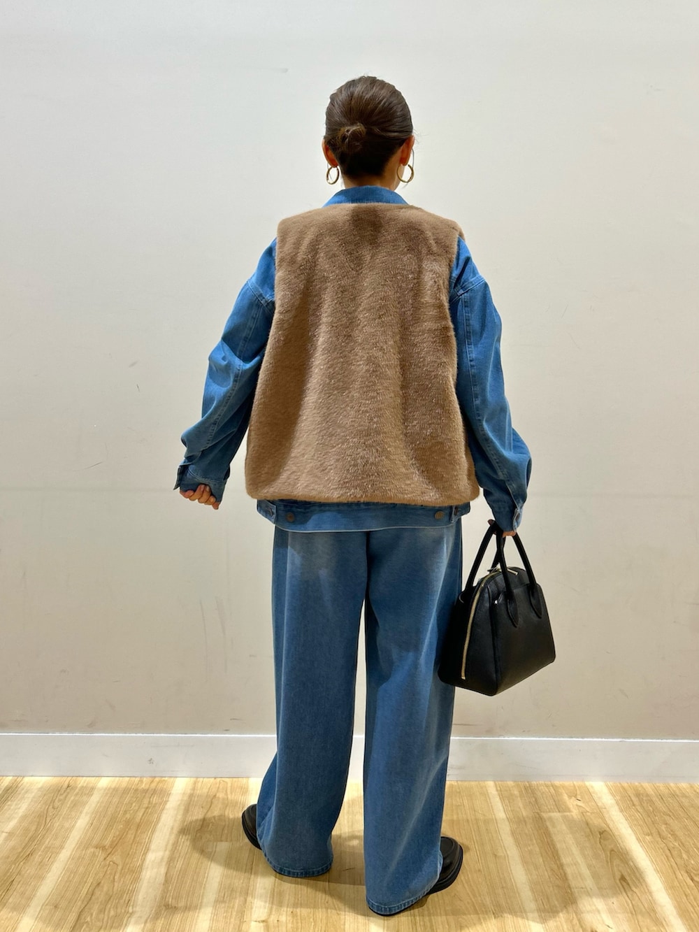ブルー系のカバーオール、ブルー系のその他パンツ、ブラウン系のダウンベストを着用したレディースの秋コーディネートの3枚目の写真
